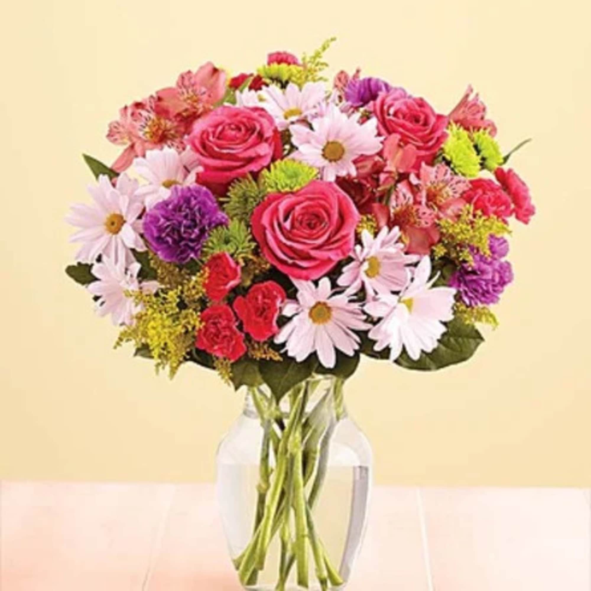 Mixed bouquet of pink roses and daisies in a clear glass vase
