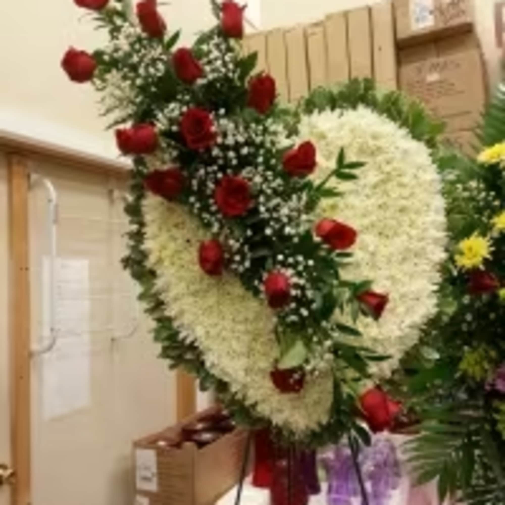 Standing floral wreath with red roses and white flowers on an easel