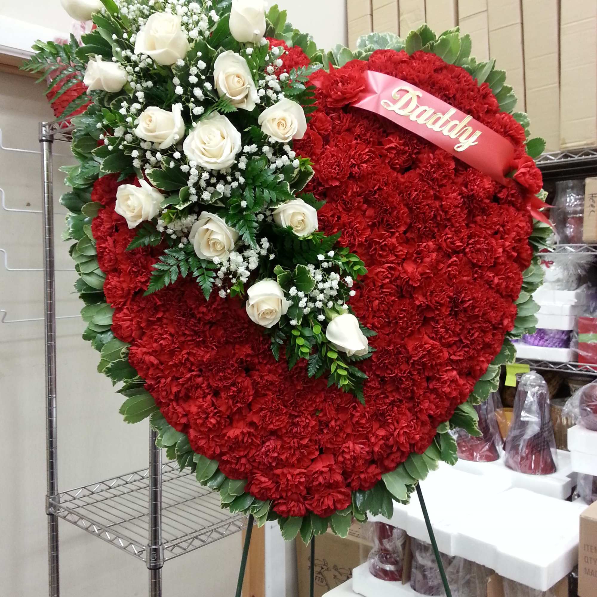 Heart-shaped red floral wreath with white roses and a pink ribbon reading Daddy