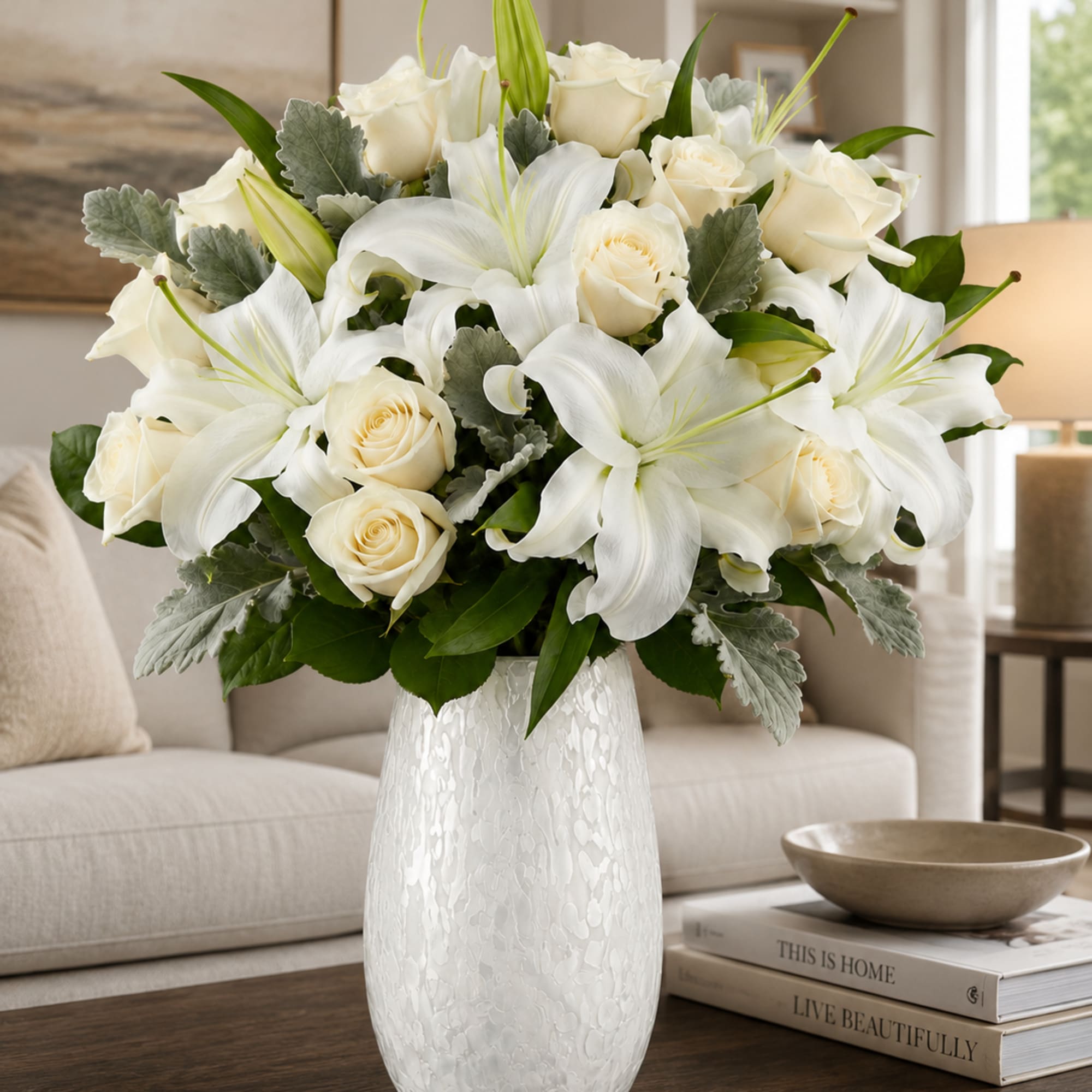 A refined mix of ivory roses and broad white lilies creates a