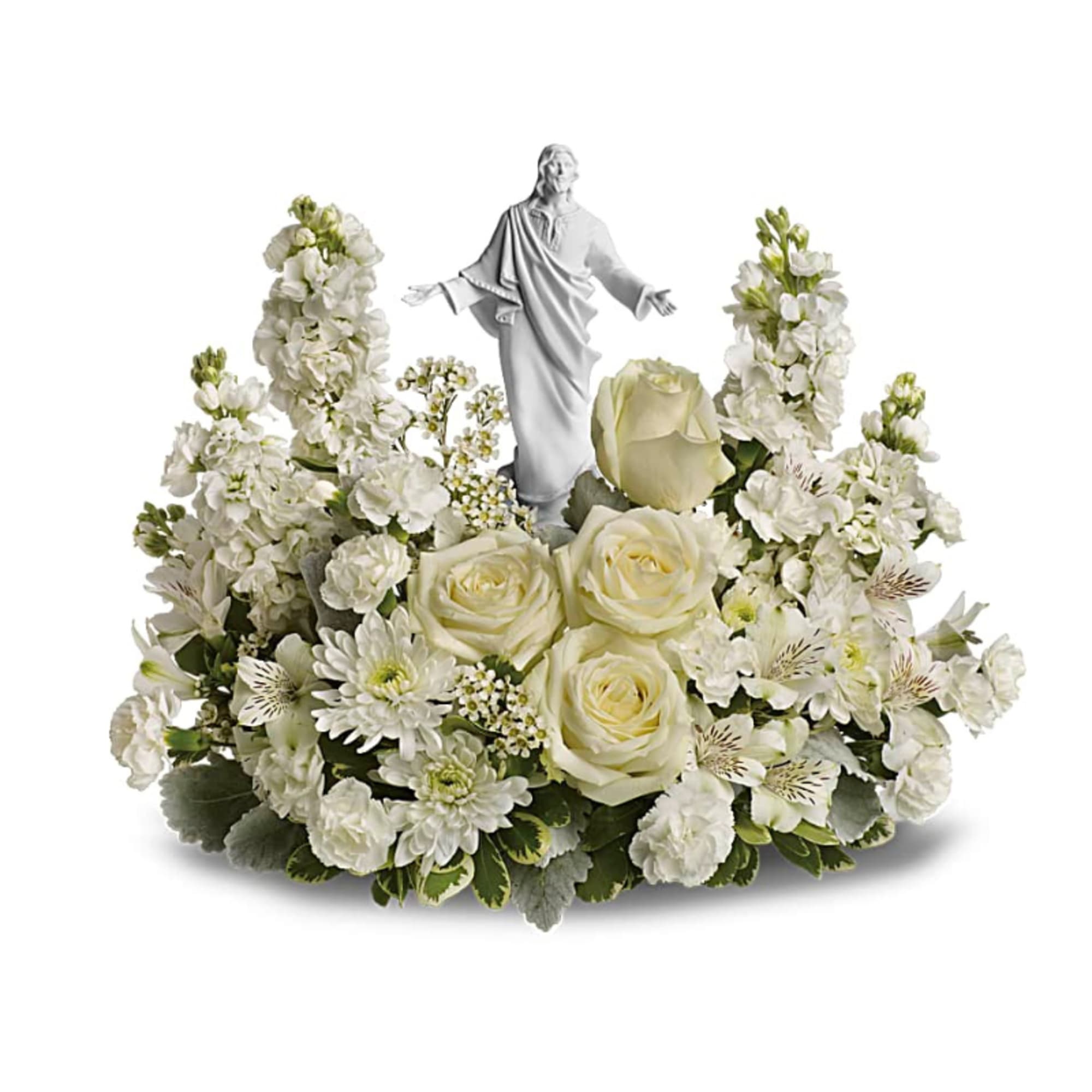 White sympathy centerpiece with roses and mixed white flowers surrounding a white religious figurine