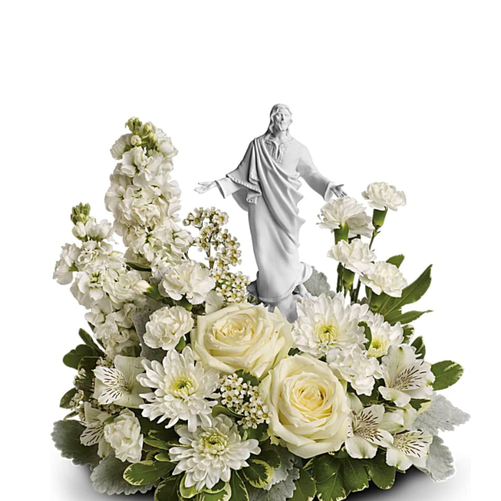 White floral arrangement with roses and mums surrounding a white Jesus figurine