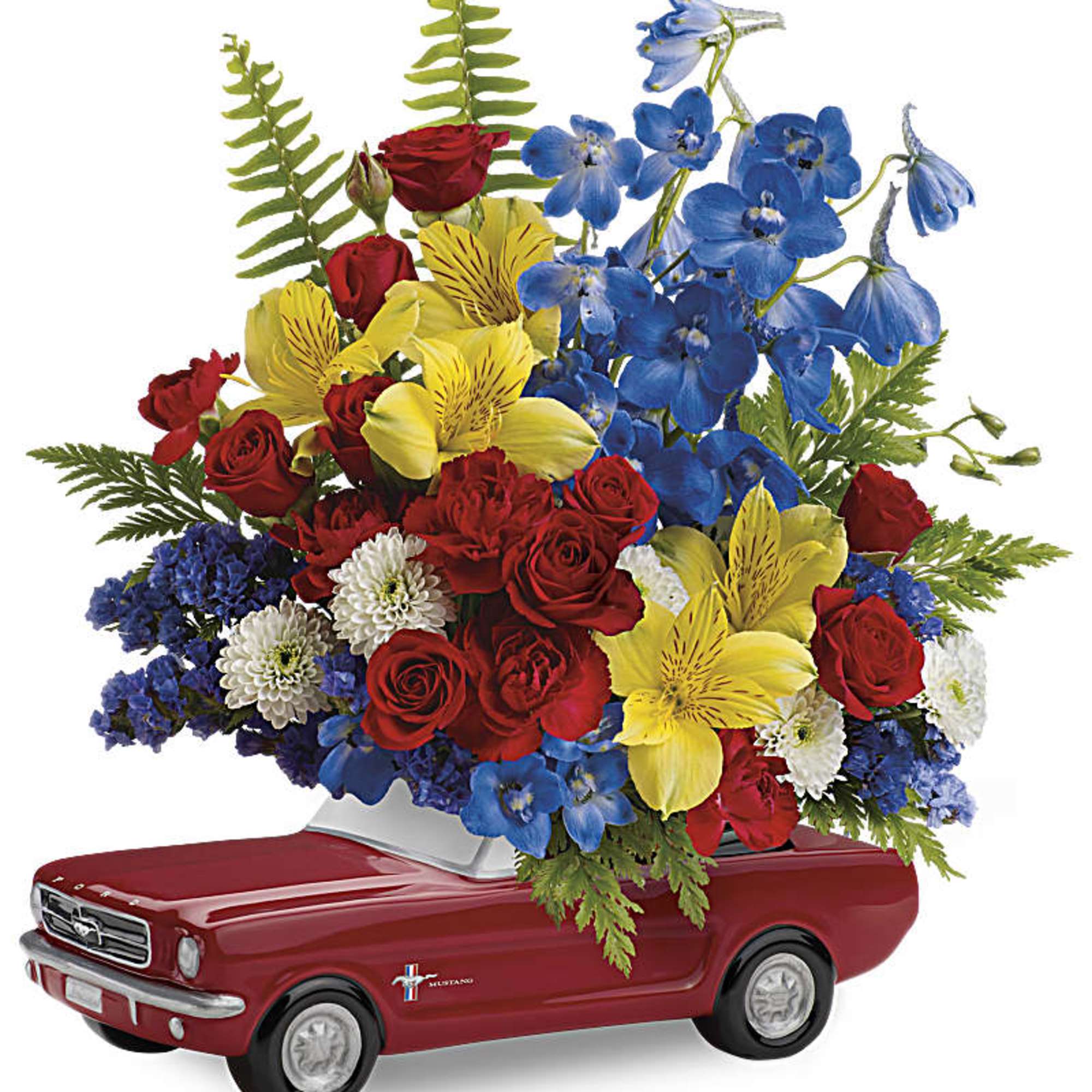 Red, yellow, blue and white flower arrangement displayed in a red ceramic car-shaped container