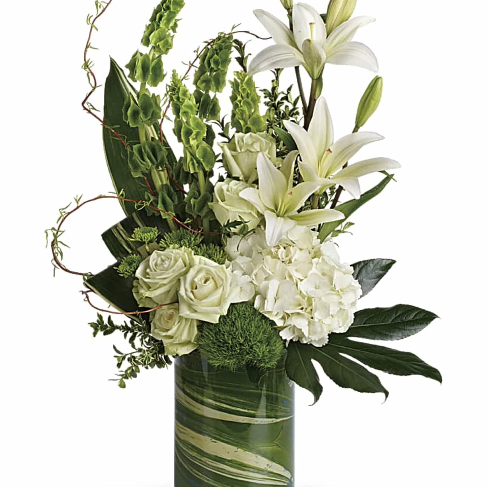 Tall white and green arrangement with lilies, roses, and hydrangeas in a clear leaf-lined glass vase