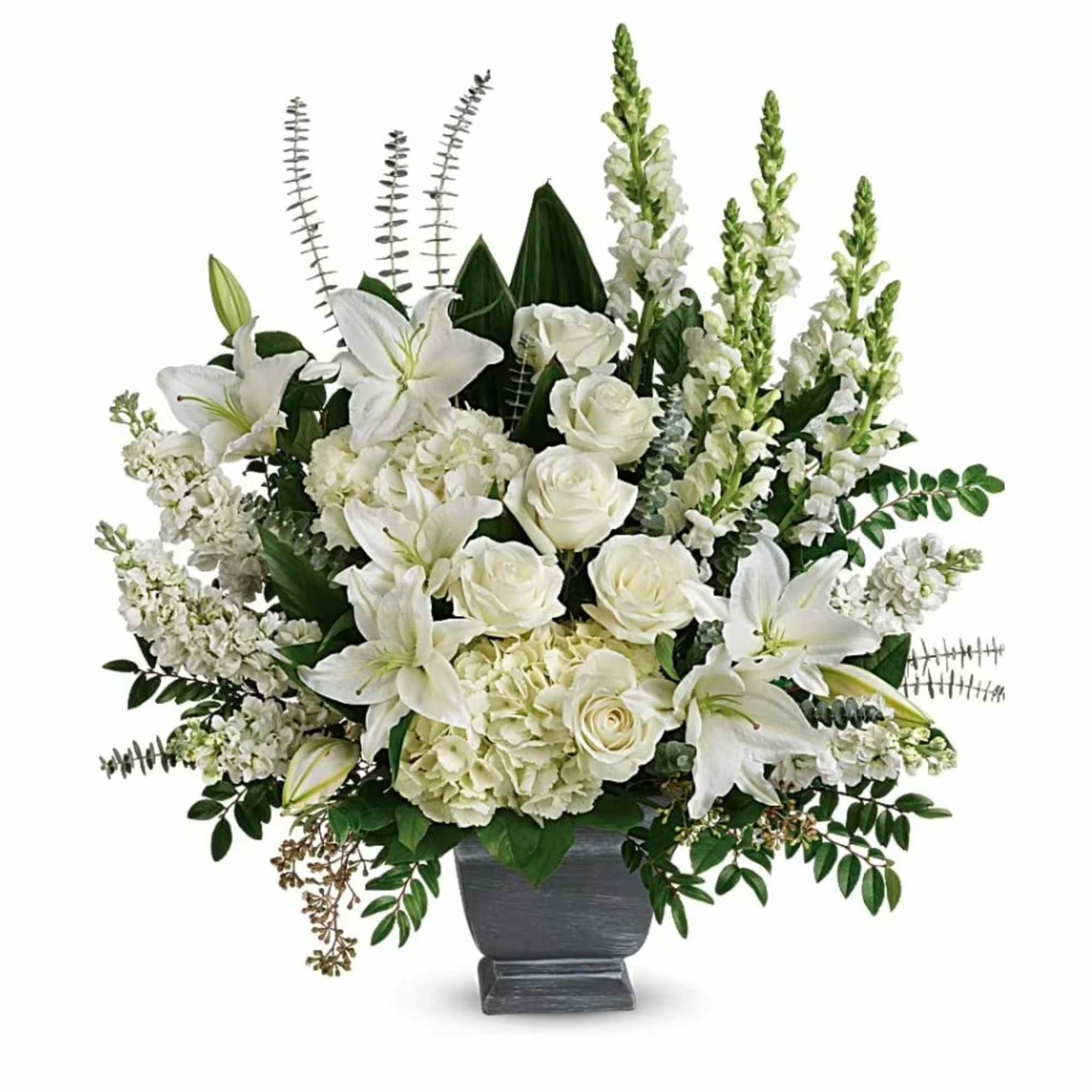 Tall white arrangement of lilies, roses, hydrangeas, and snapdragons in a gray pedestal vase