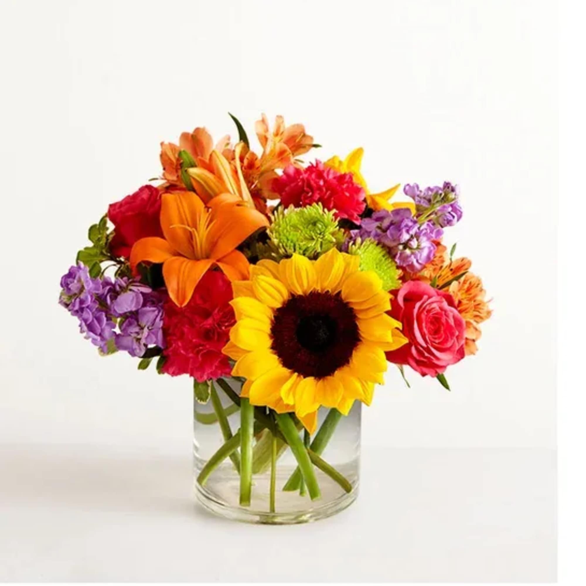 Bright mixed bouquet with sunflower, orange lilies, and pink blooms in a clear glass vase