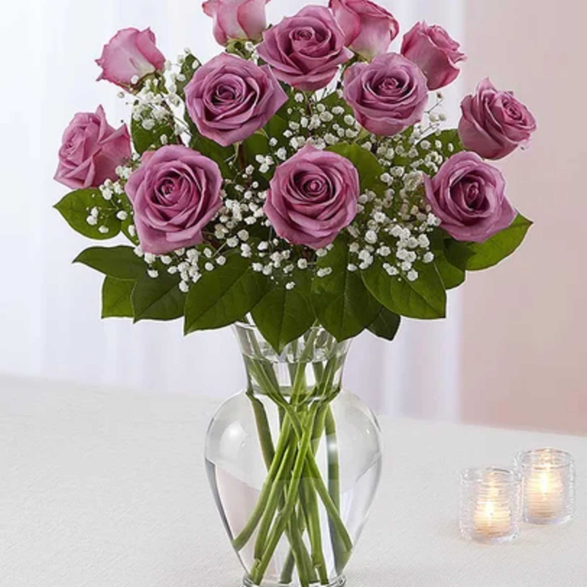 Lavender roses arranged in a clear glass vase with baby's breath