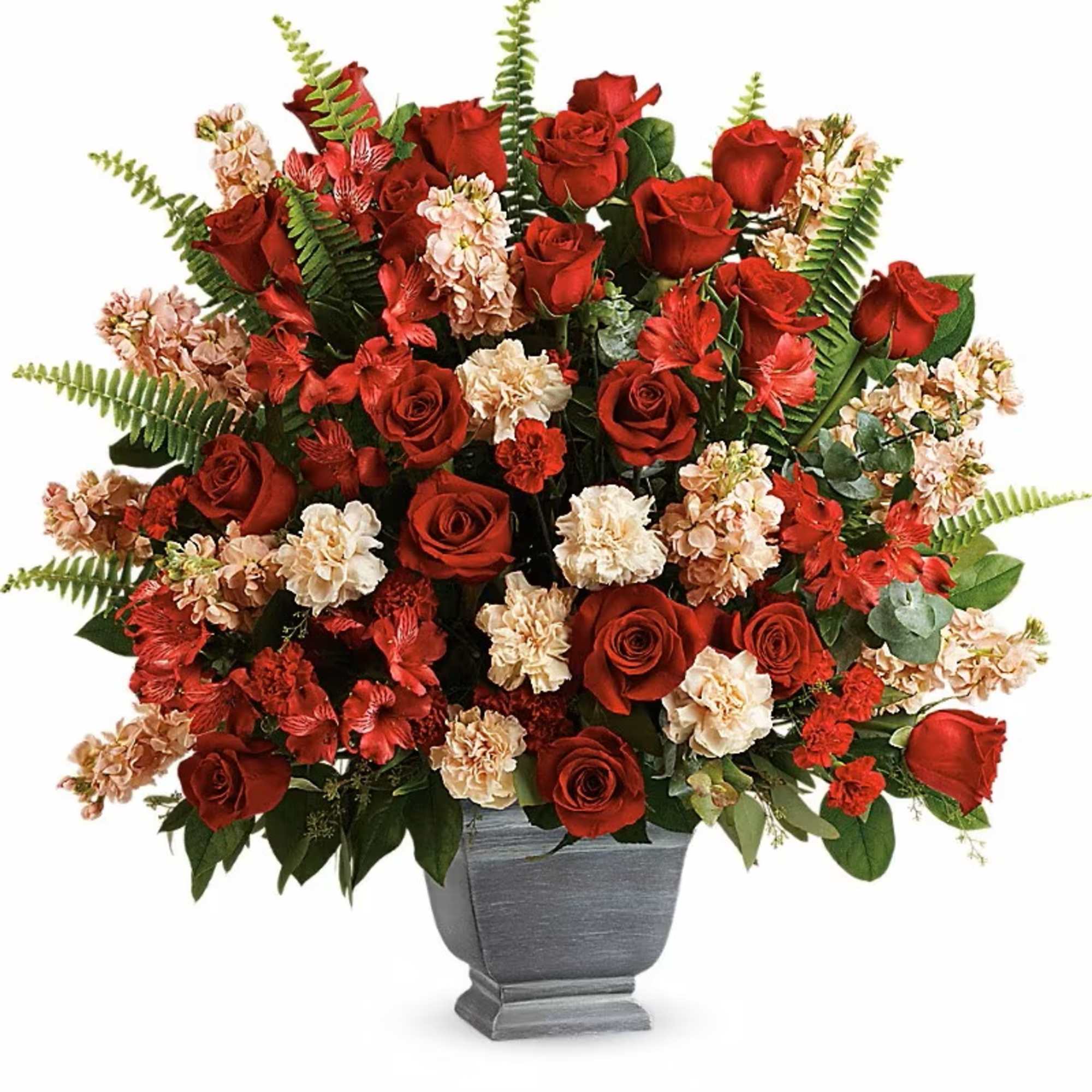 Red roses and peach carnations in a gray urn vase