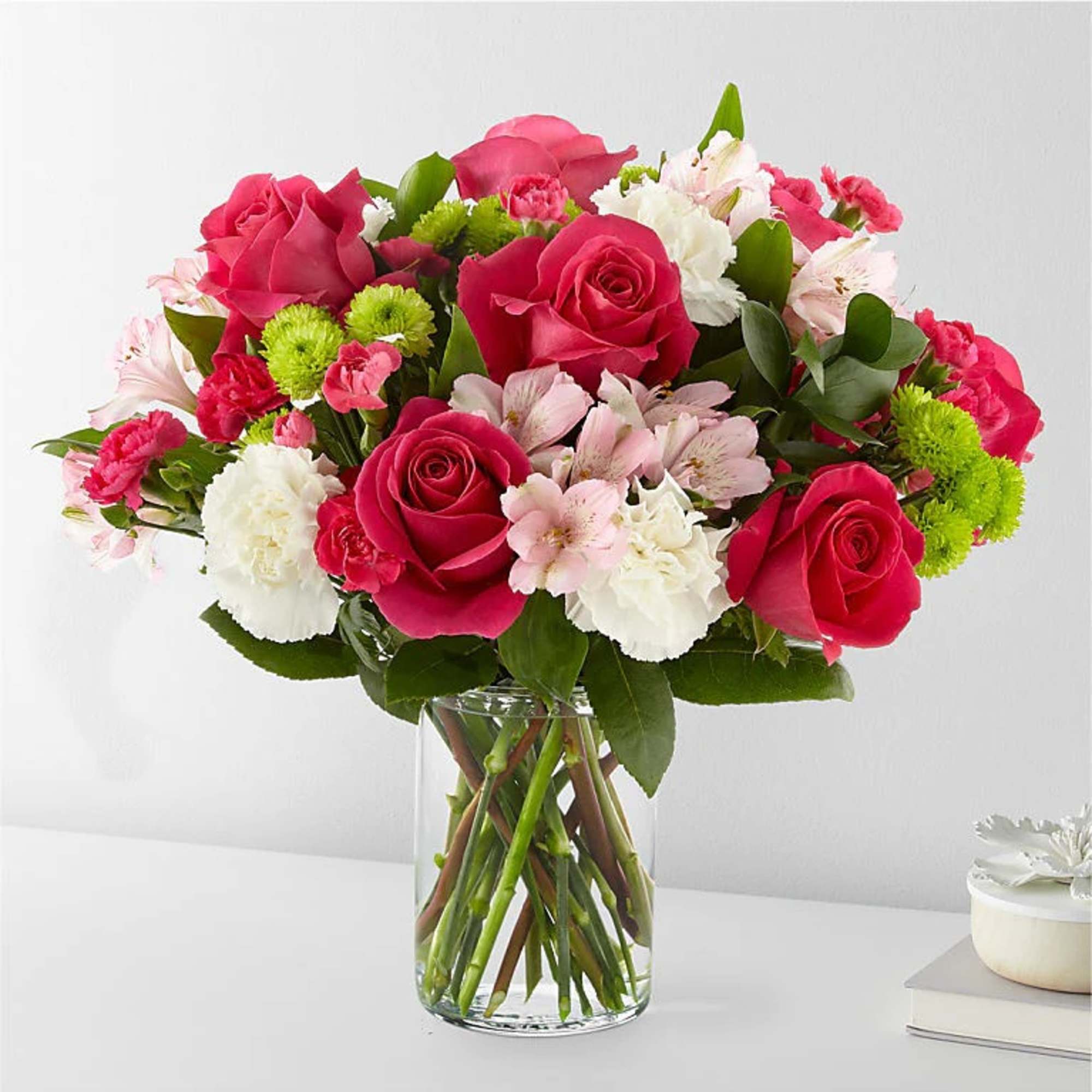 Pink roses and mixed flowers arranged in a clear glass vase