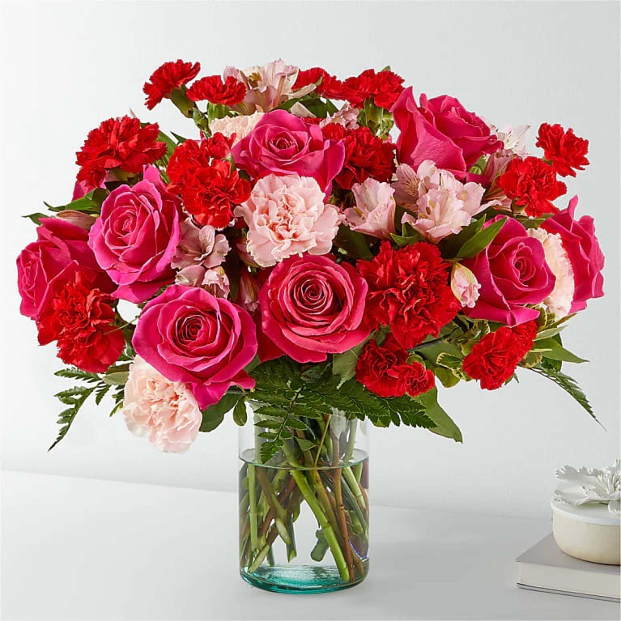 Bouquet of pink roses and red carnations in a glass vase