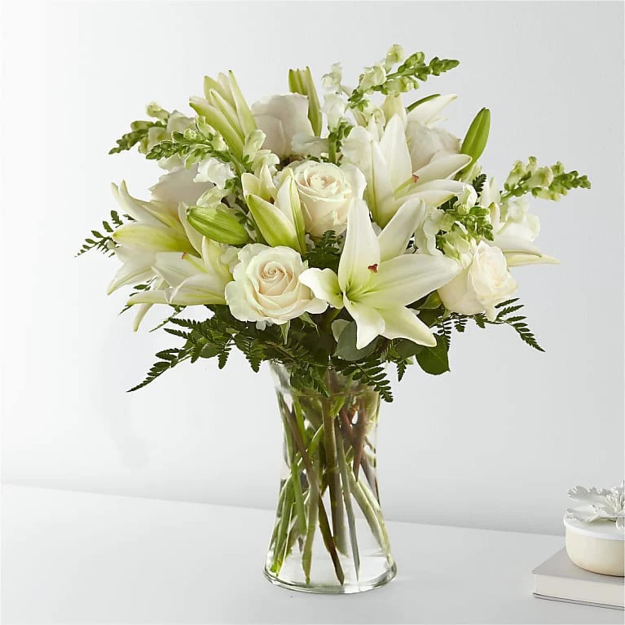 White lilies and roses arranged in a clear glass vase