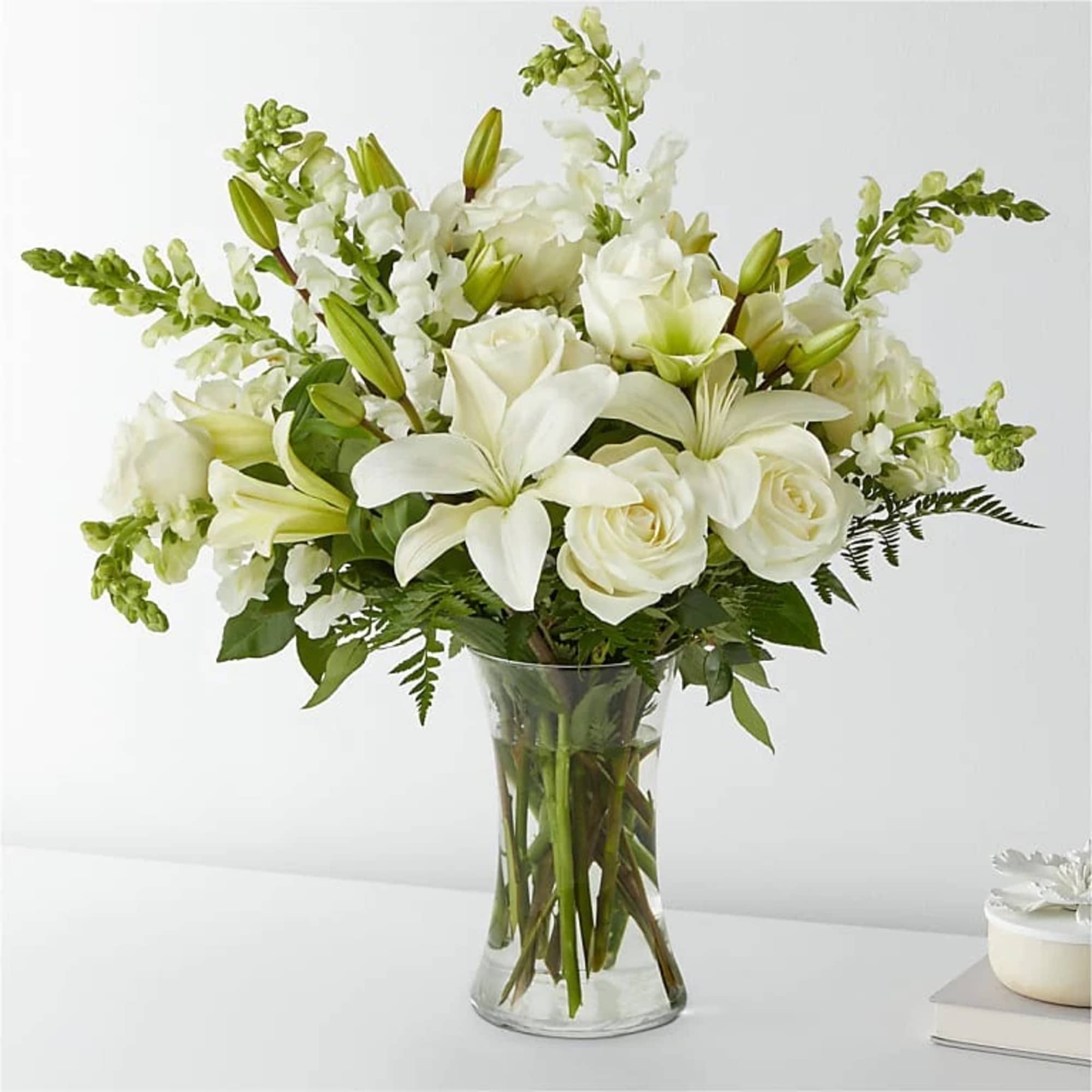 White lilies and roses in a clear glass vase