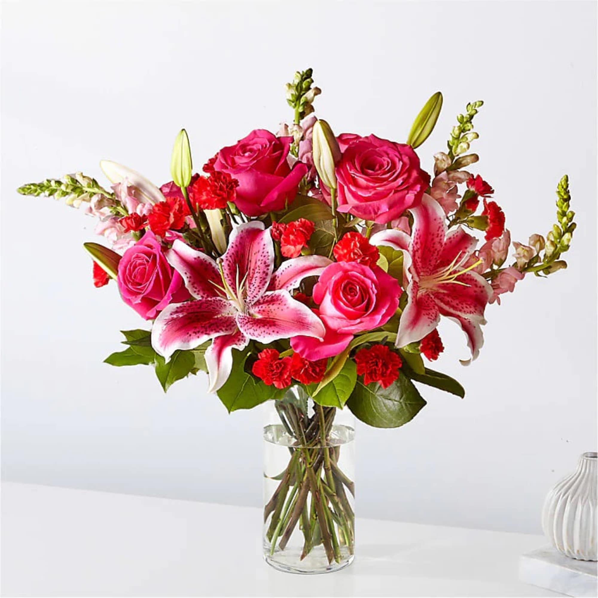 Pink roses and stargazer lilies in a clear glass vase