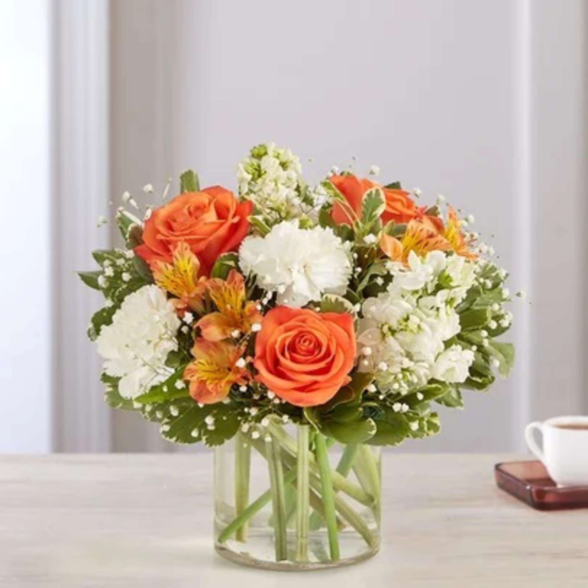 Orange roses and white flowers in a clear glass vase