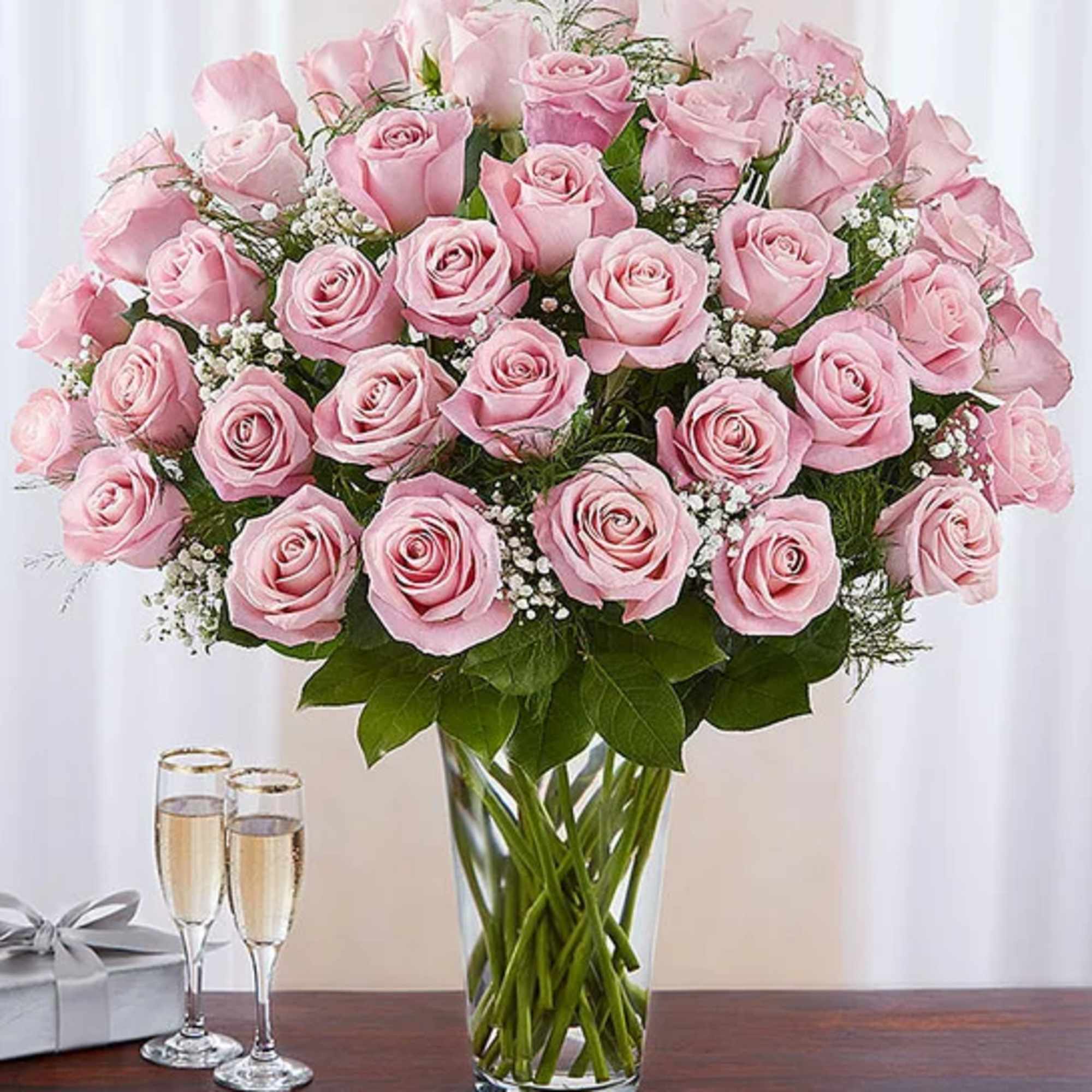 Pink roses arranged in a clear glass vase with baby's breath
