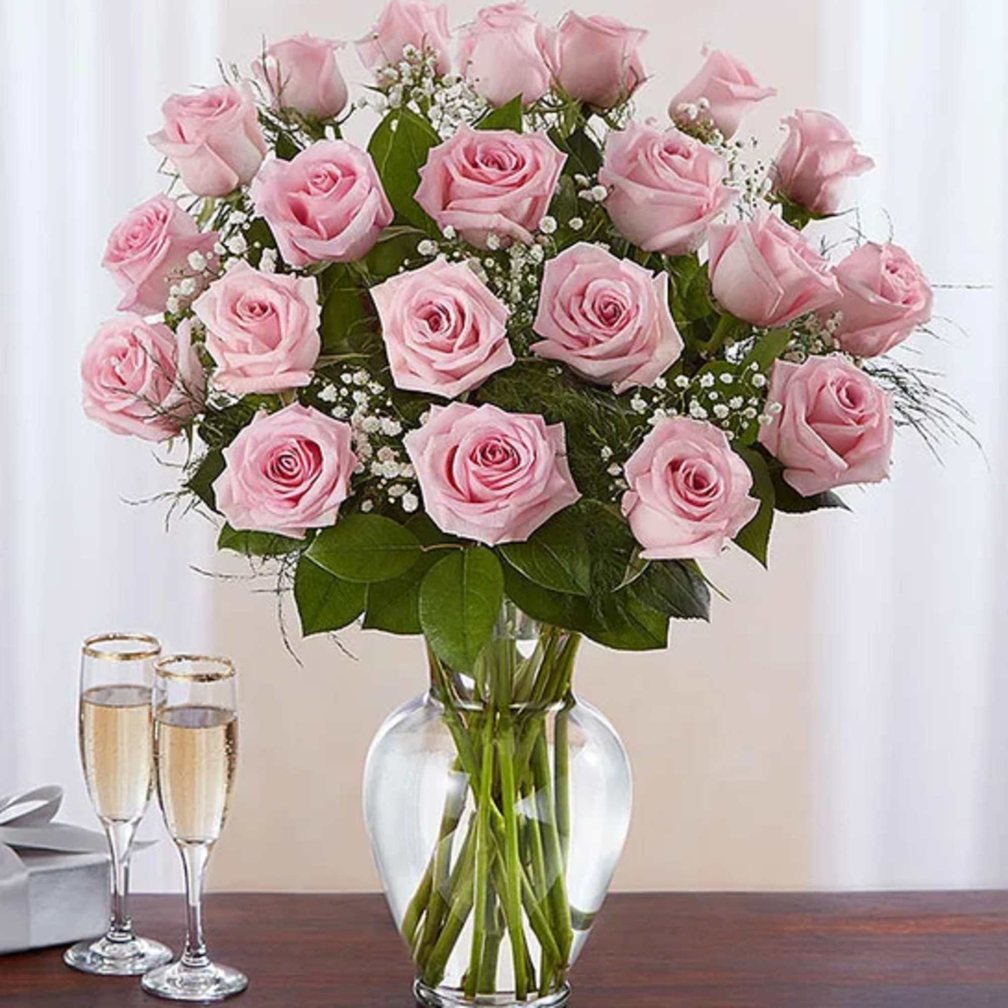Pink roses arranged in a clear glass vase with baby's breath