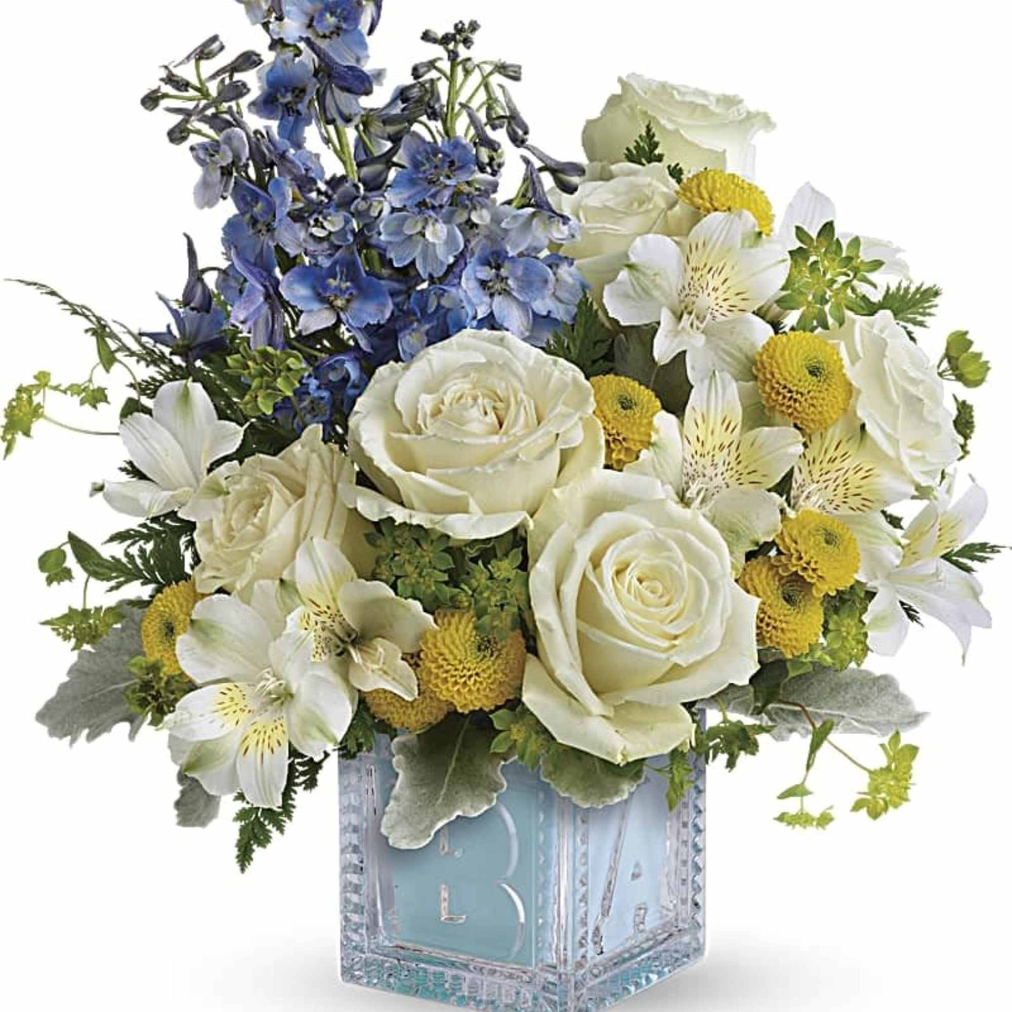 White roses and blue flowers arranged in a glass cube vase