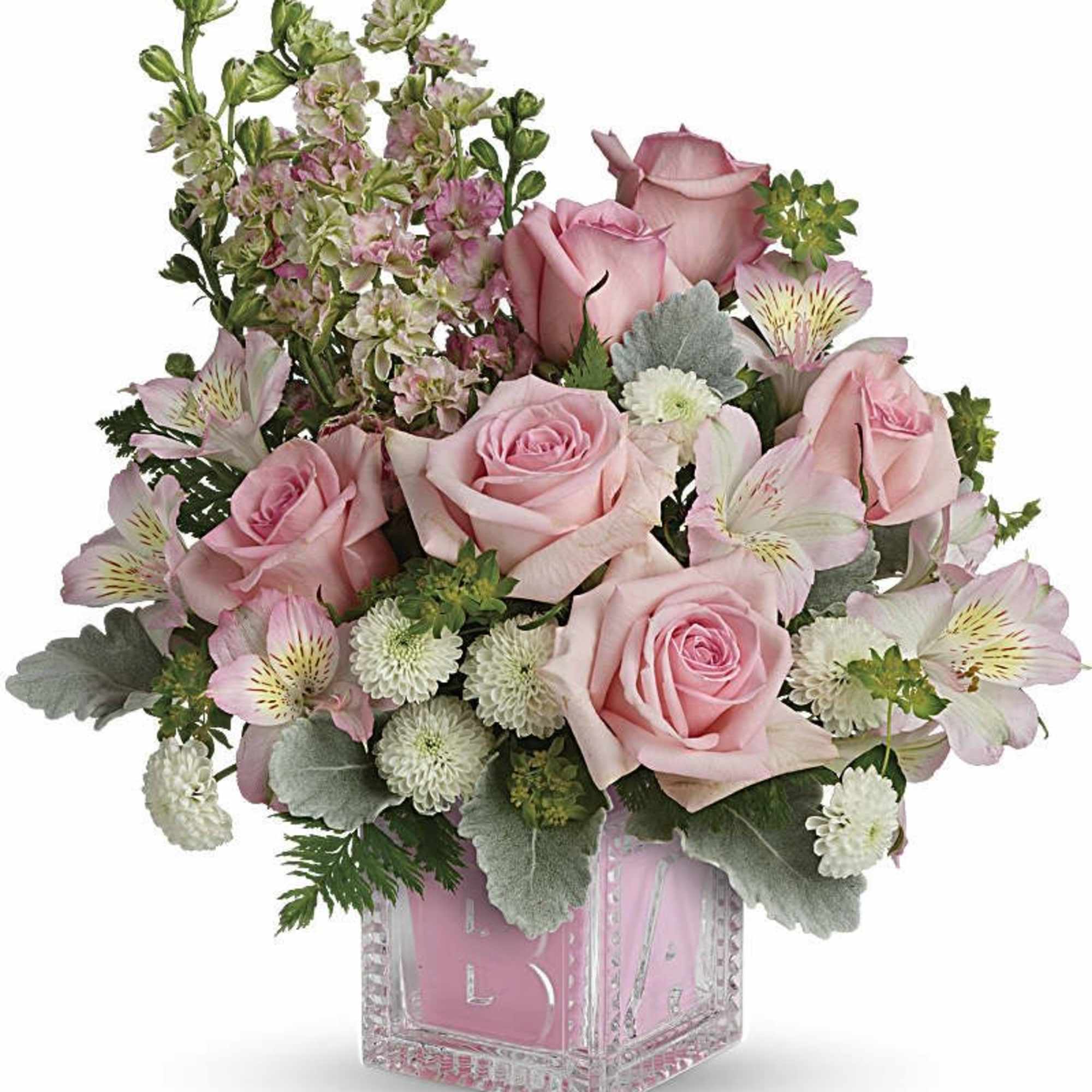 Pink roses and mixed blooms arranged in a clear square vase