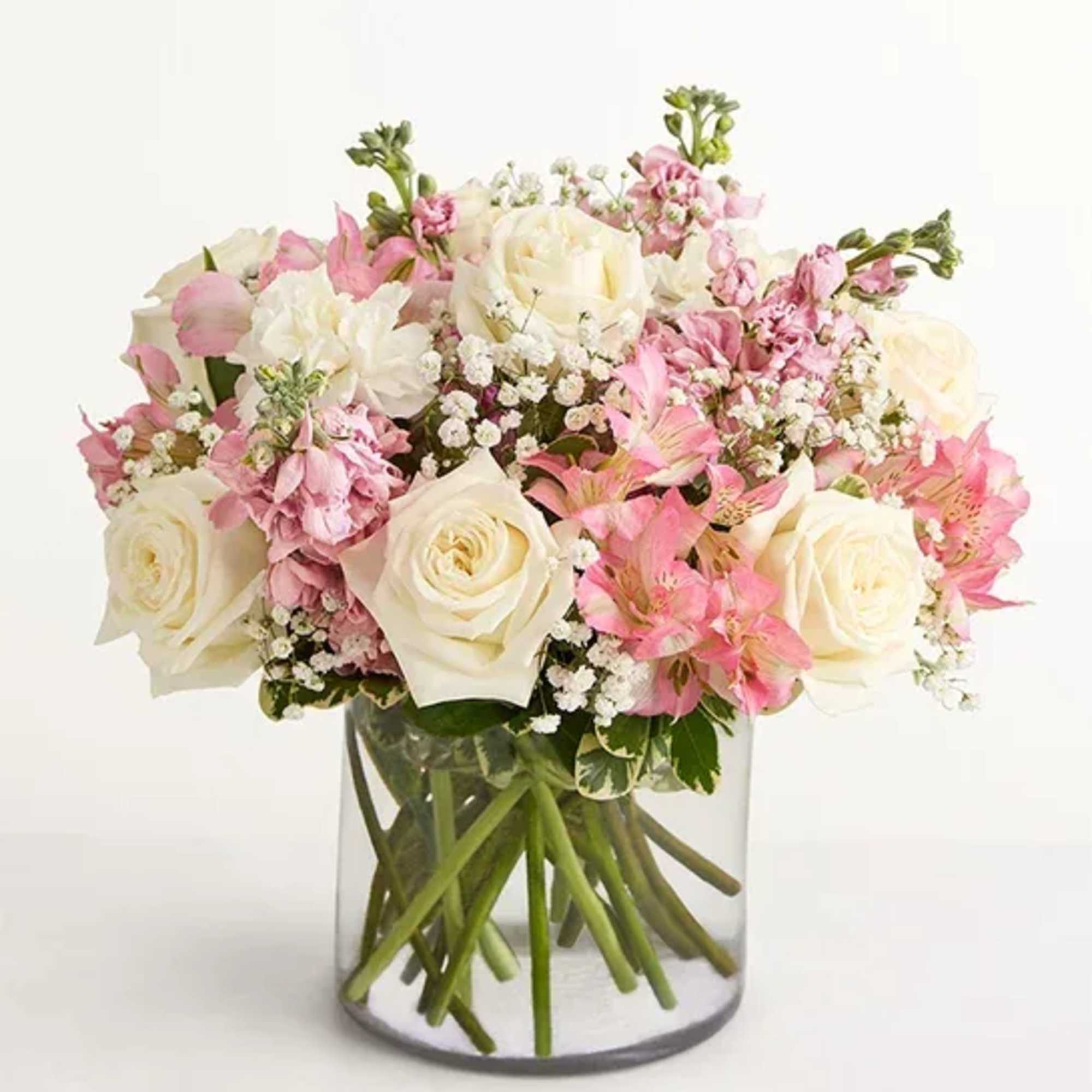 Pink and white bouquet of roses and mixed blooms in a clear glass vase