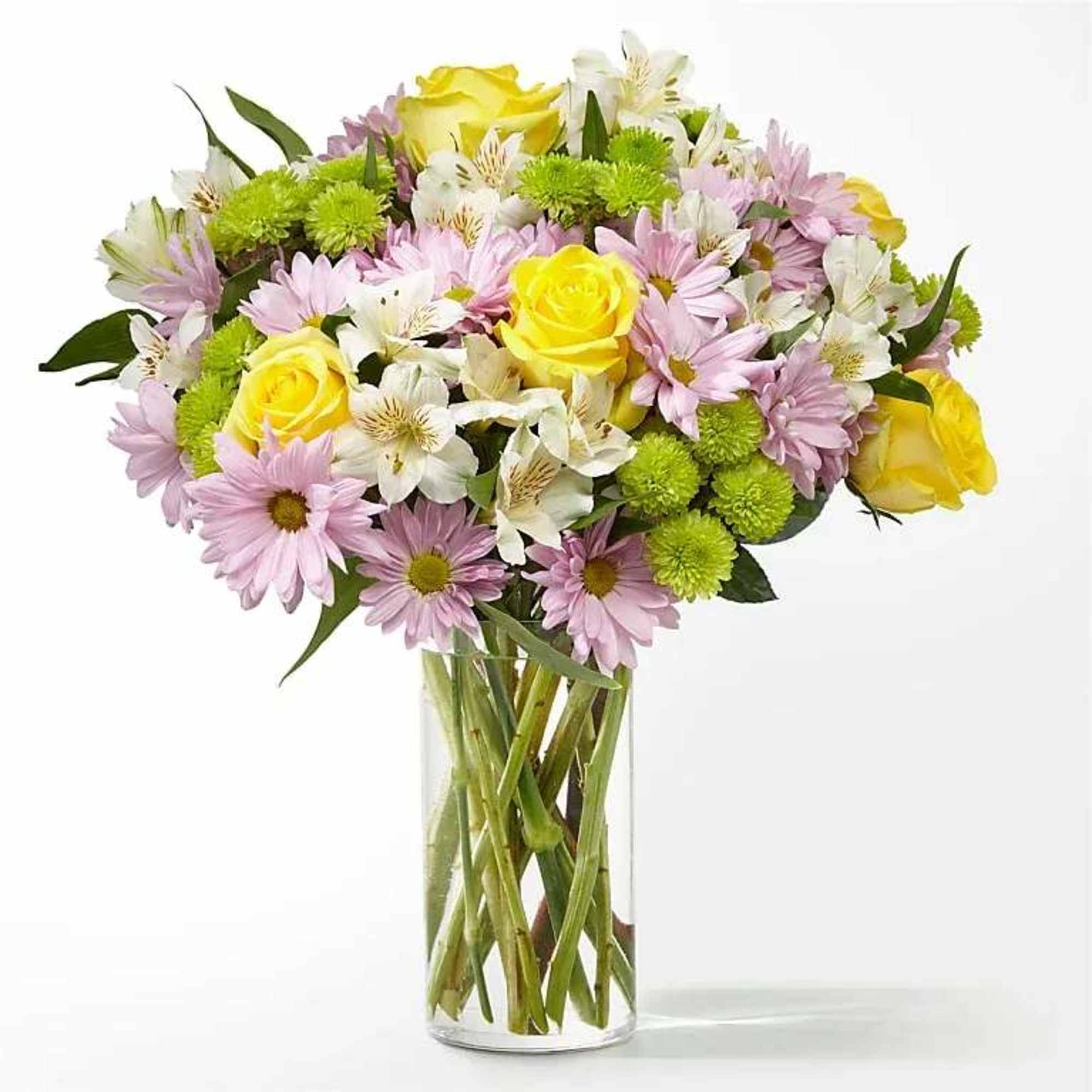 Mixed bouquet of yellow roses, pink daisies, green mums, and white alstroemeria in a clear glass vase