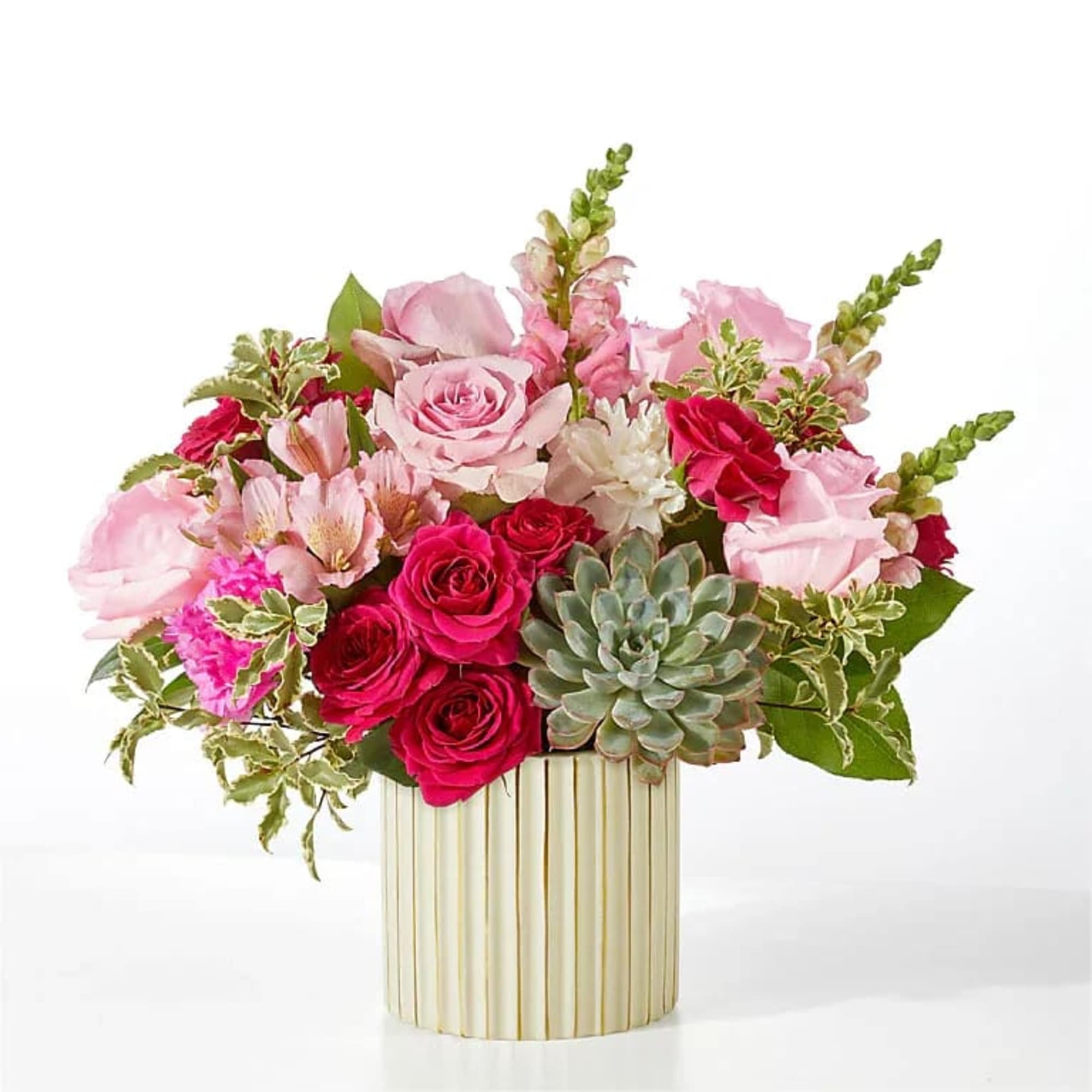 Pink roses and mixed blooms in a ribbed gold vase with a succulent accent