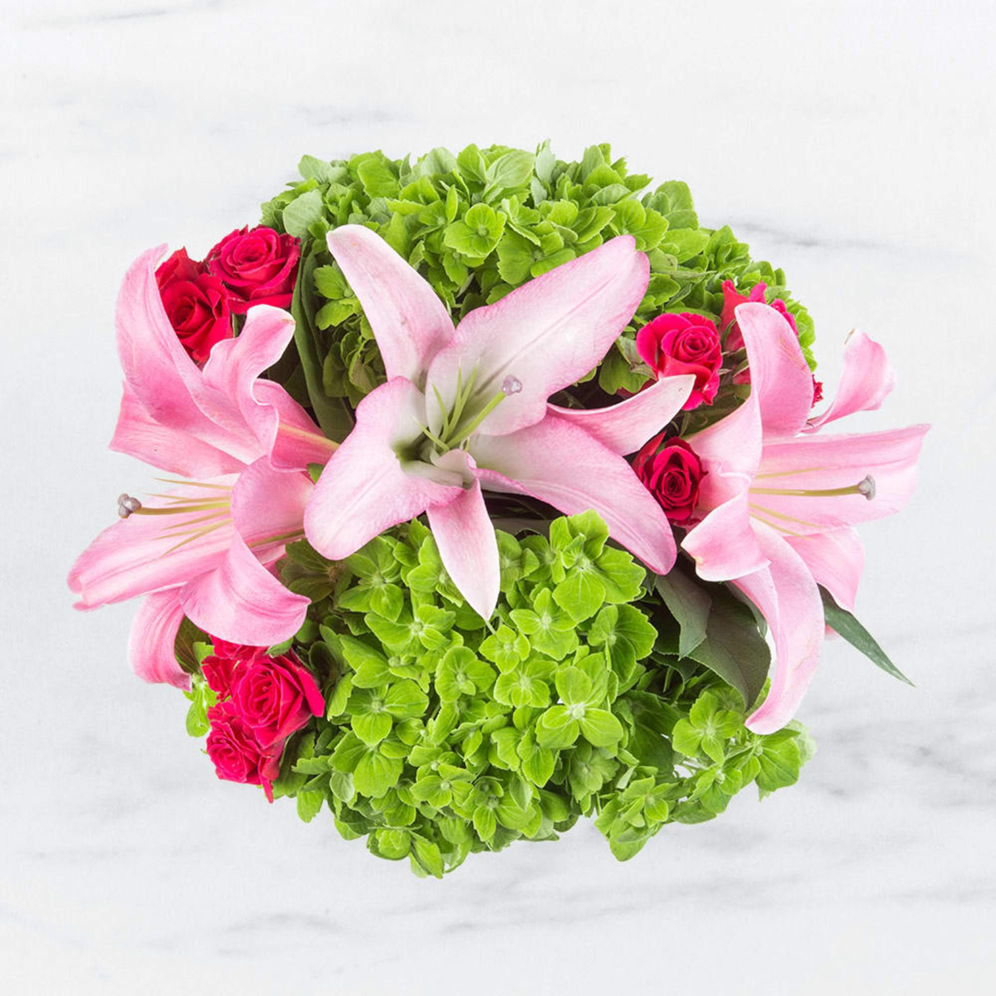 Pink lilies and hot pink roses arranged with bright green hydrangeas