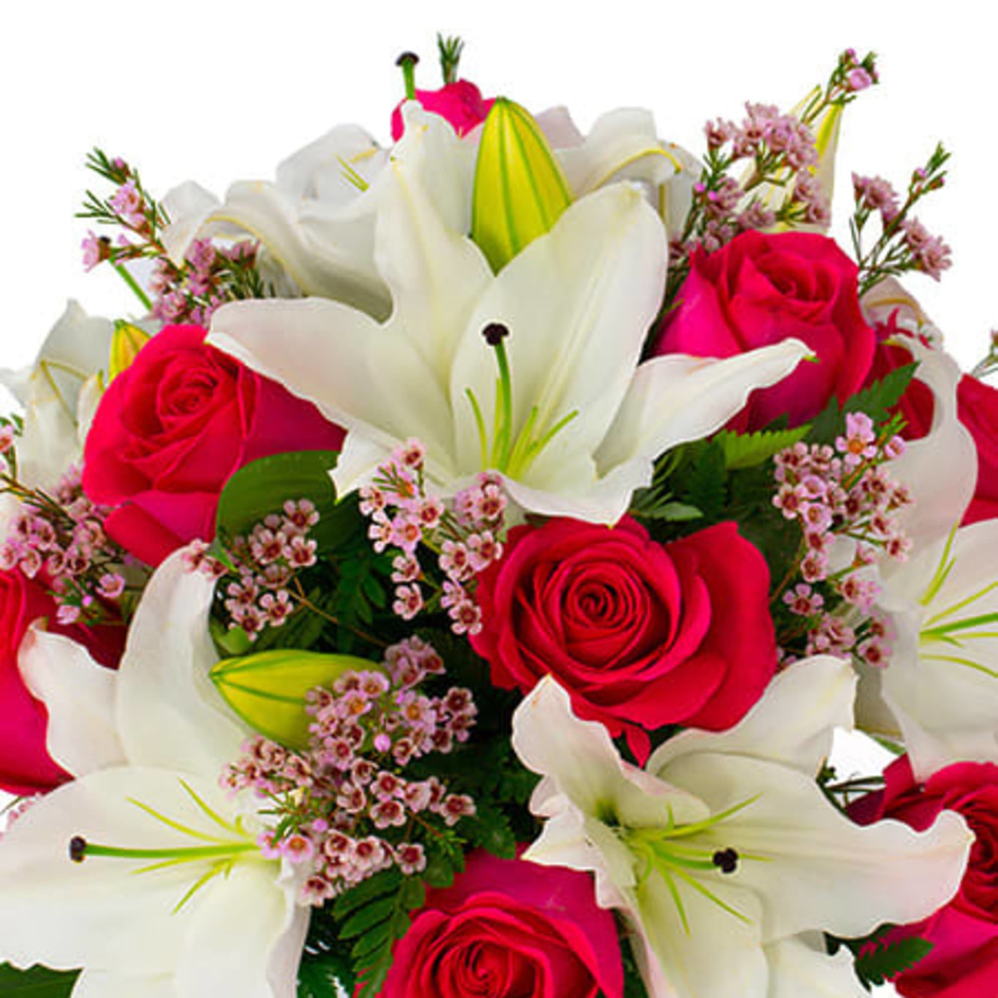 Arrangement of white lilies and hot pink roses with small pink blooms in a glass vase