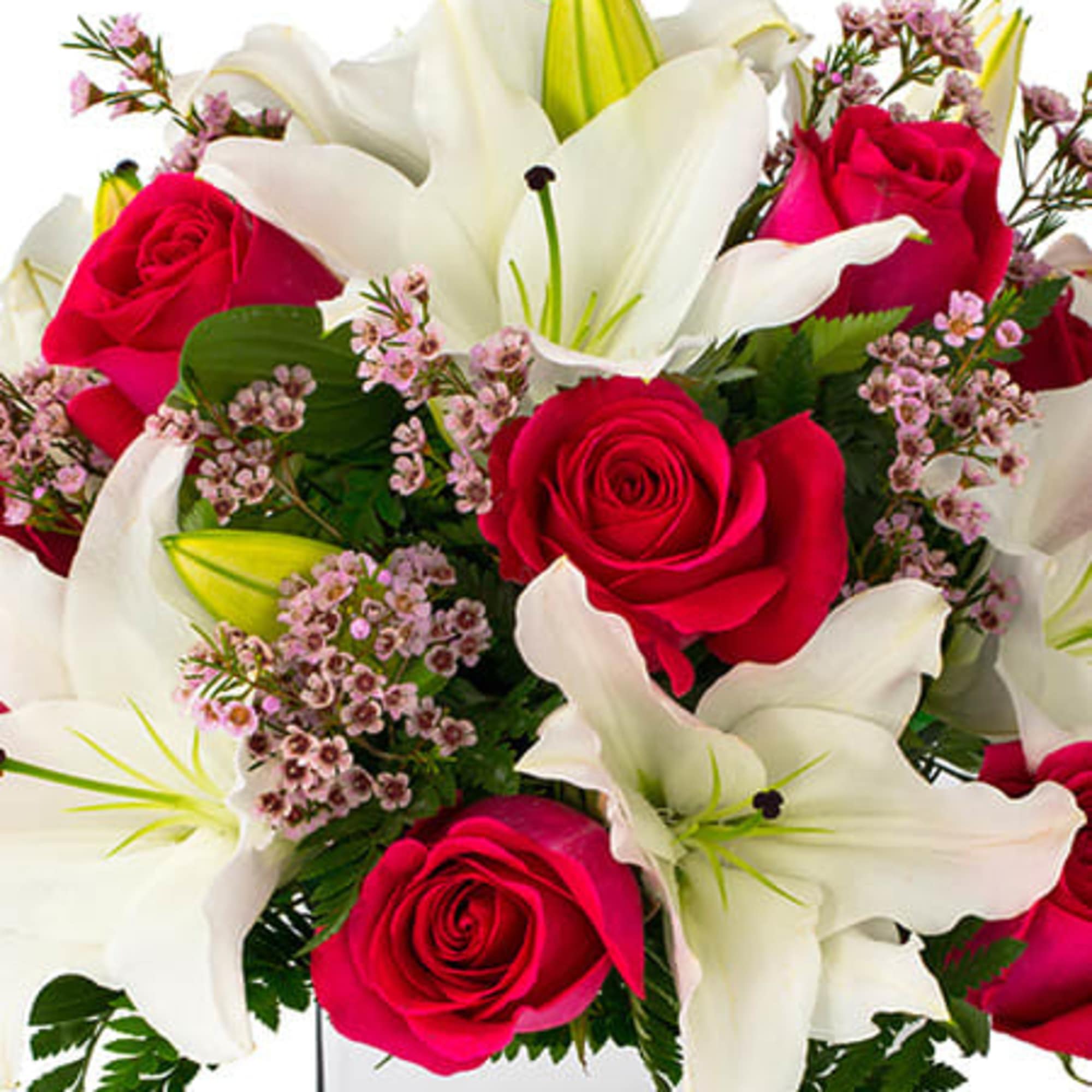 Arrangement of white lilies, red roses, and small pink flowers in a clear glass cube vase