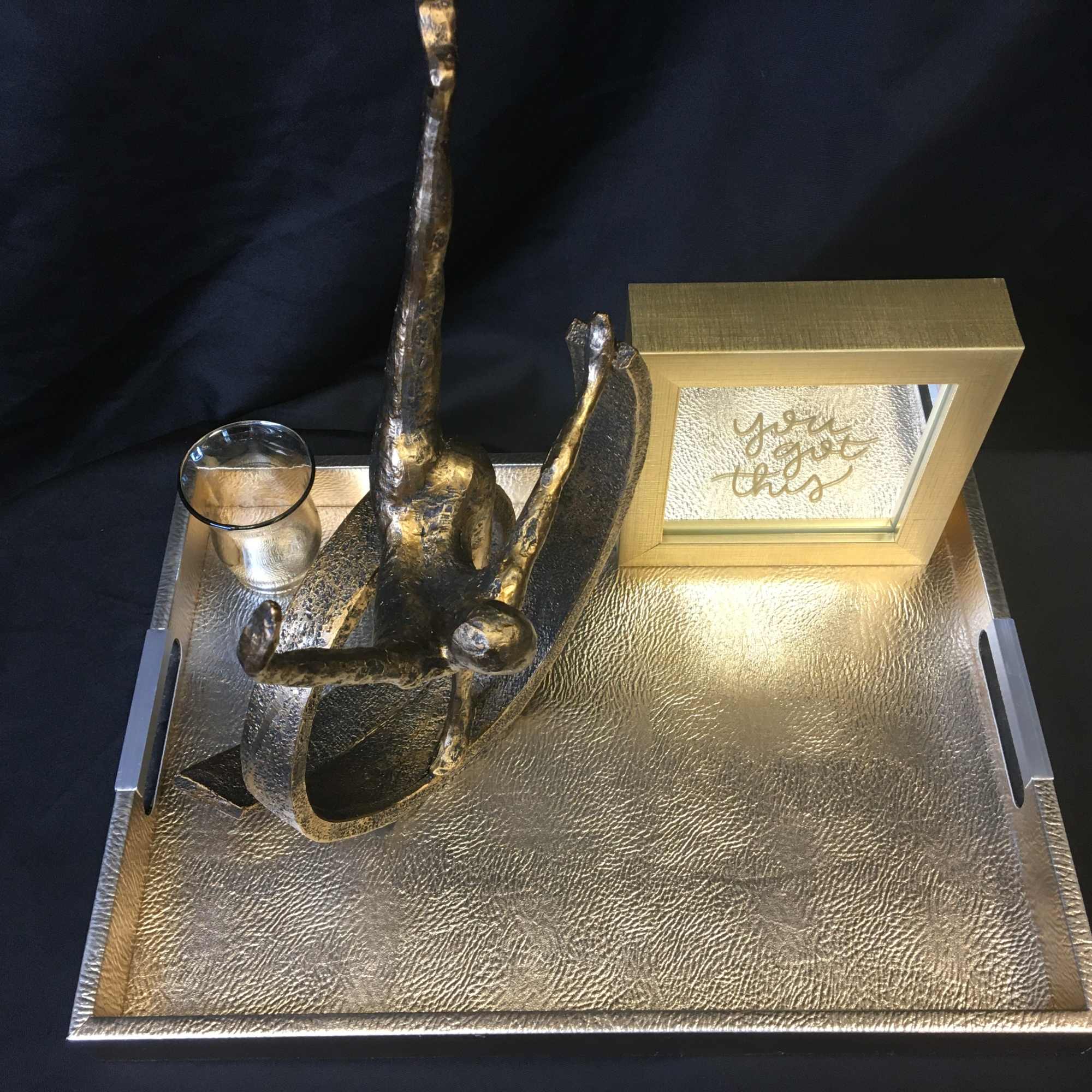 Gold tray with a small sculpture, candle holder, and framed sign