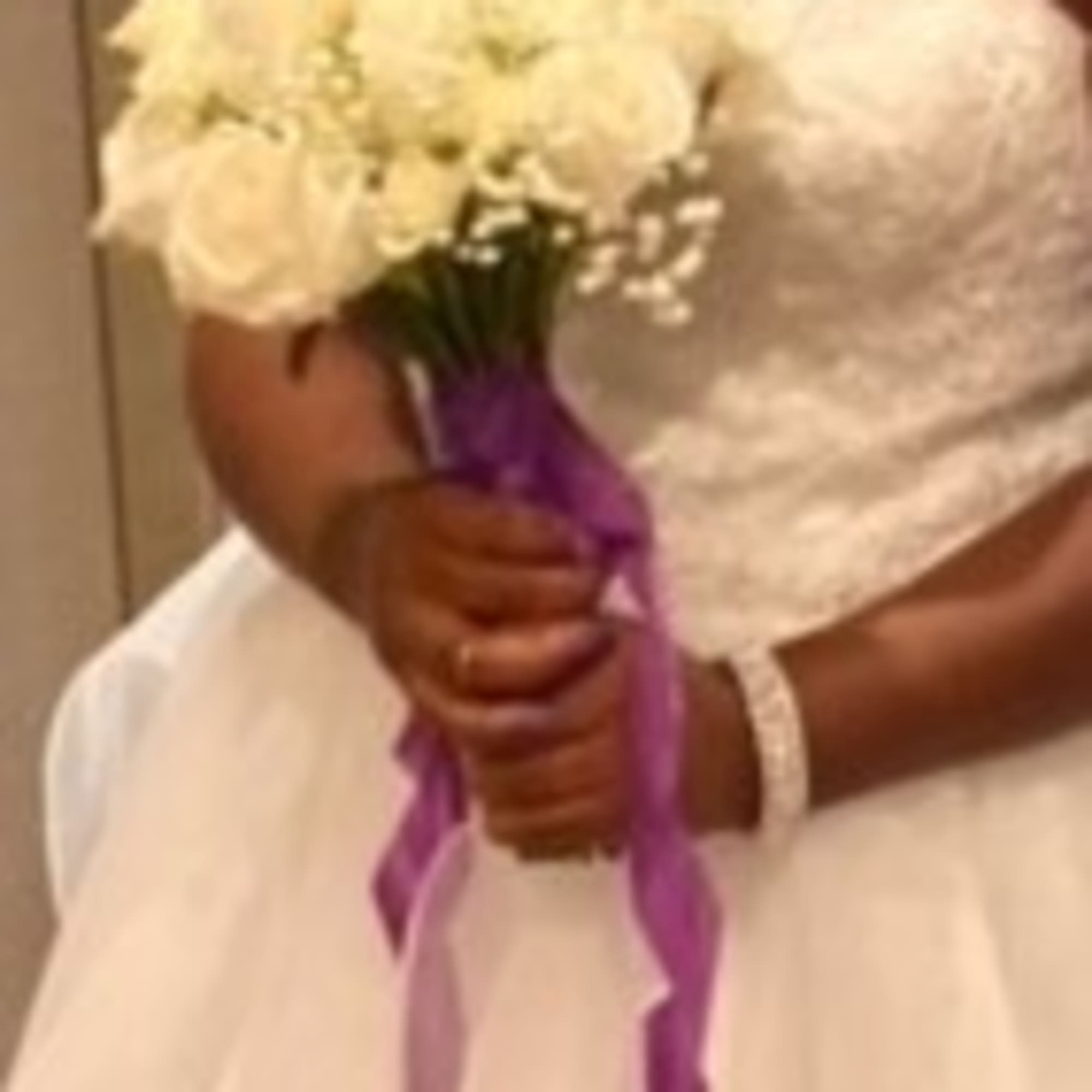Bride holding a white bouquet with a purple ribbon