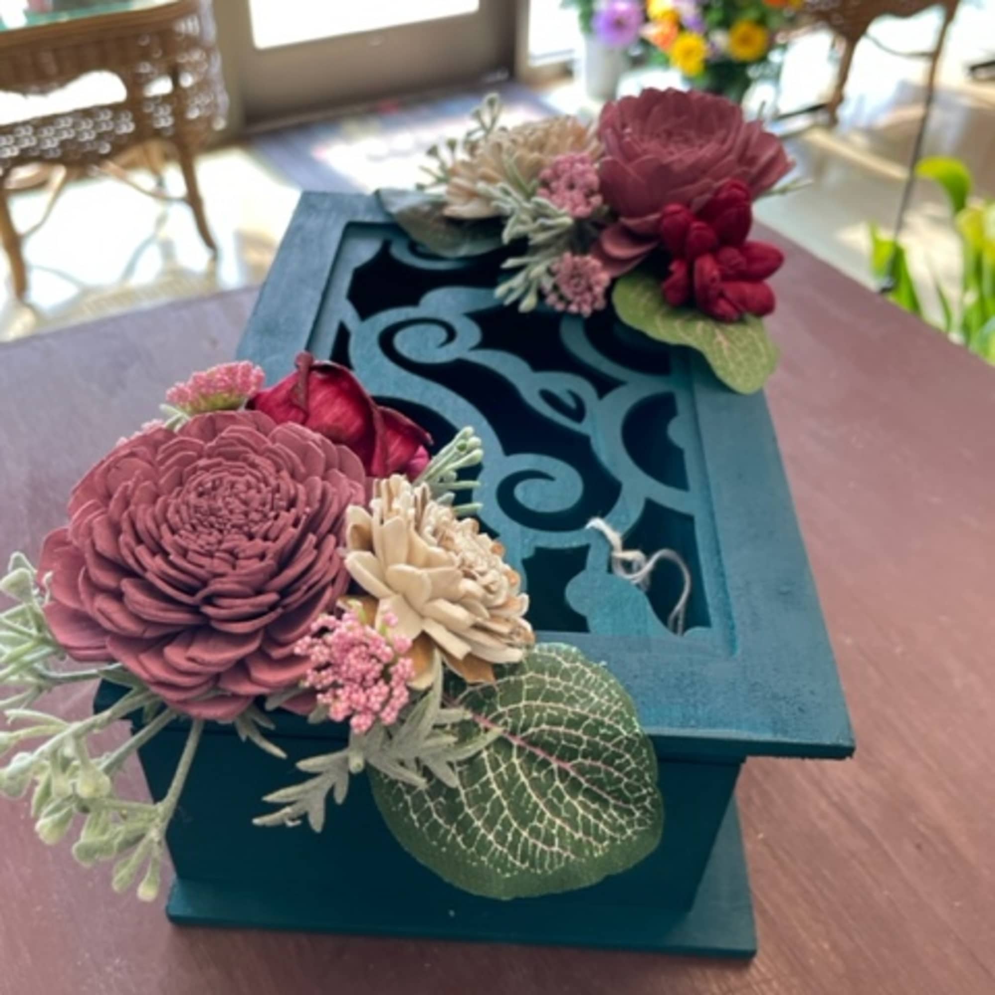 Two floral-decorated teal gift boxes on a table