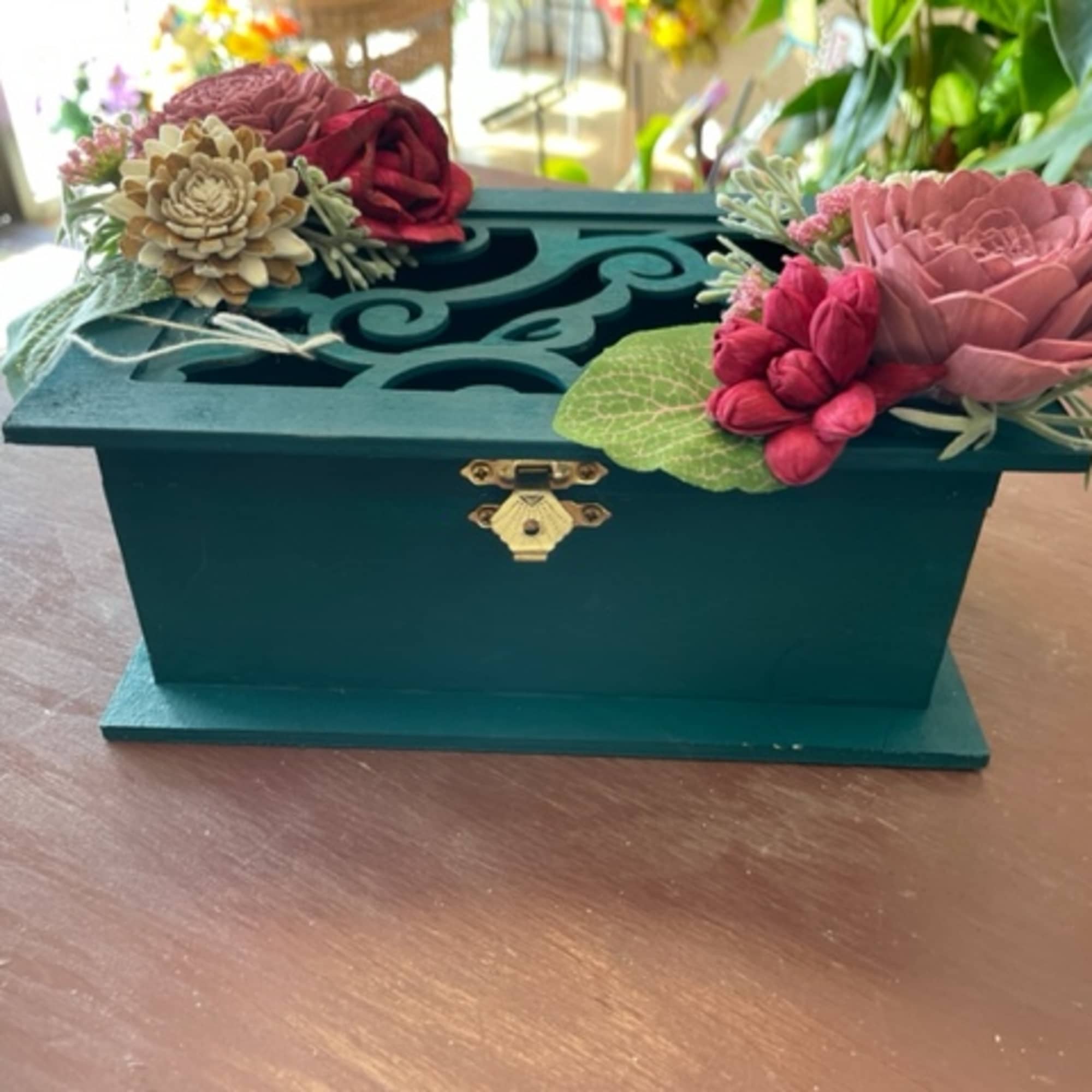 Teal decorative box with artificial flowers on top