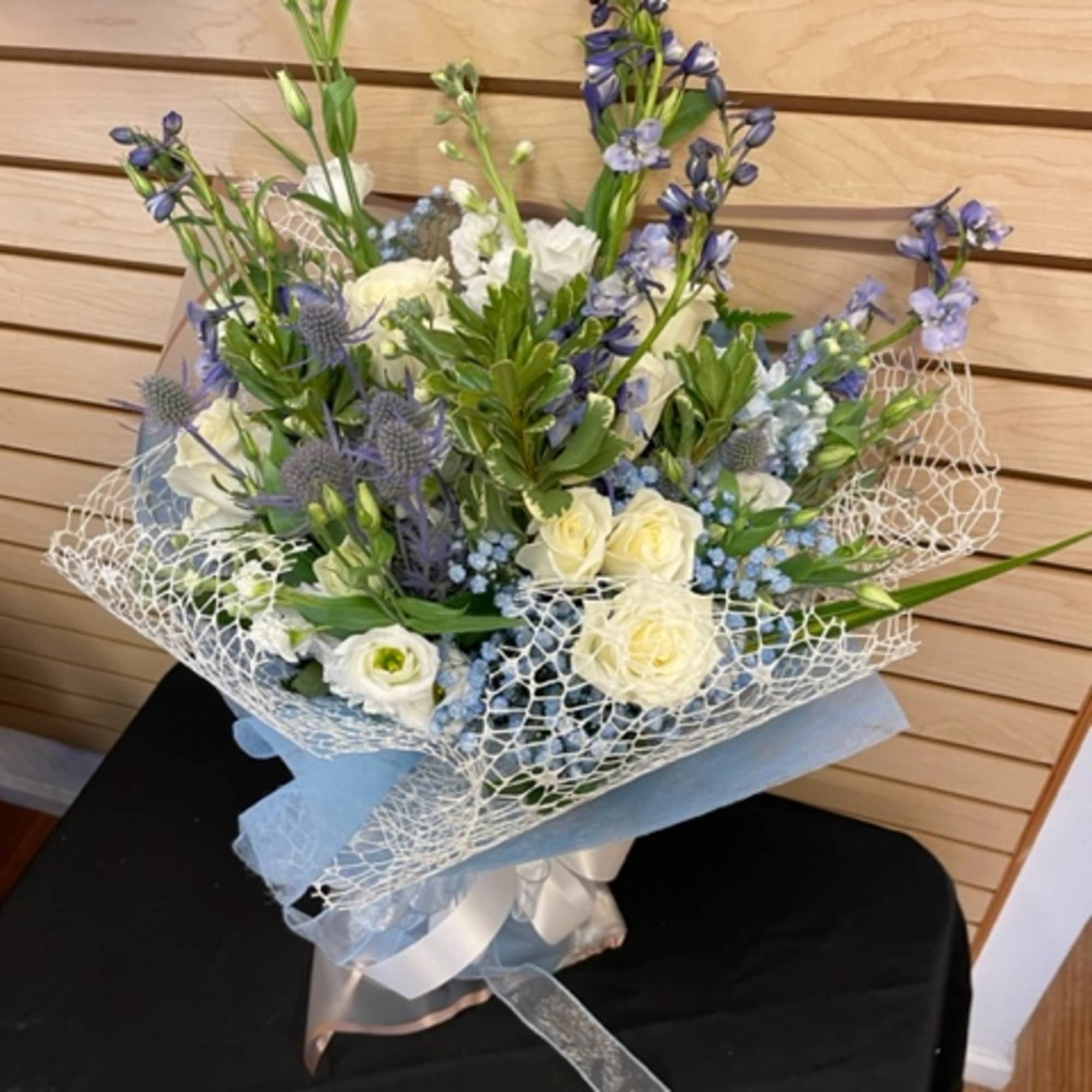 Bouquet of white and blue flowers wrapped in pale blue paper