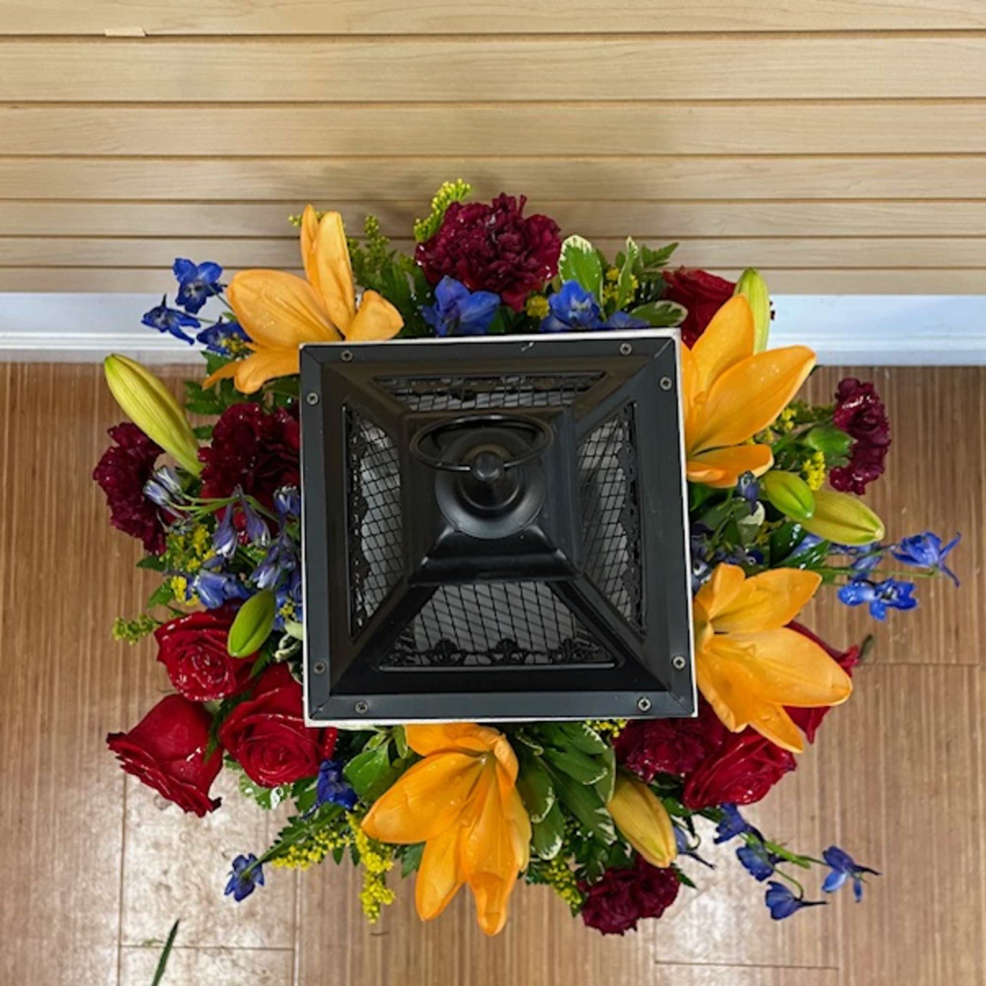 Colorful floral arrangement around a black speaker box