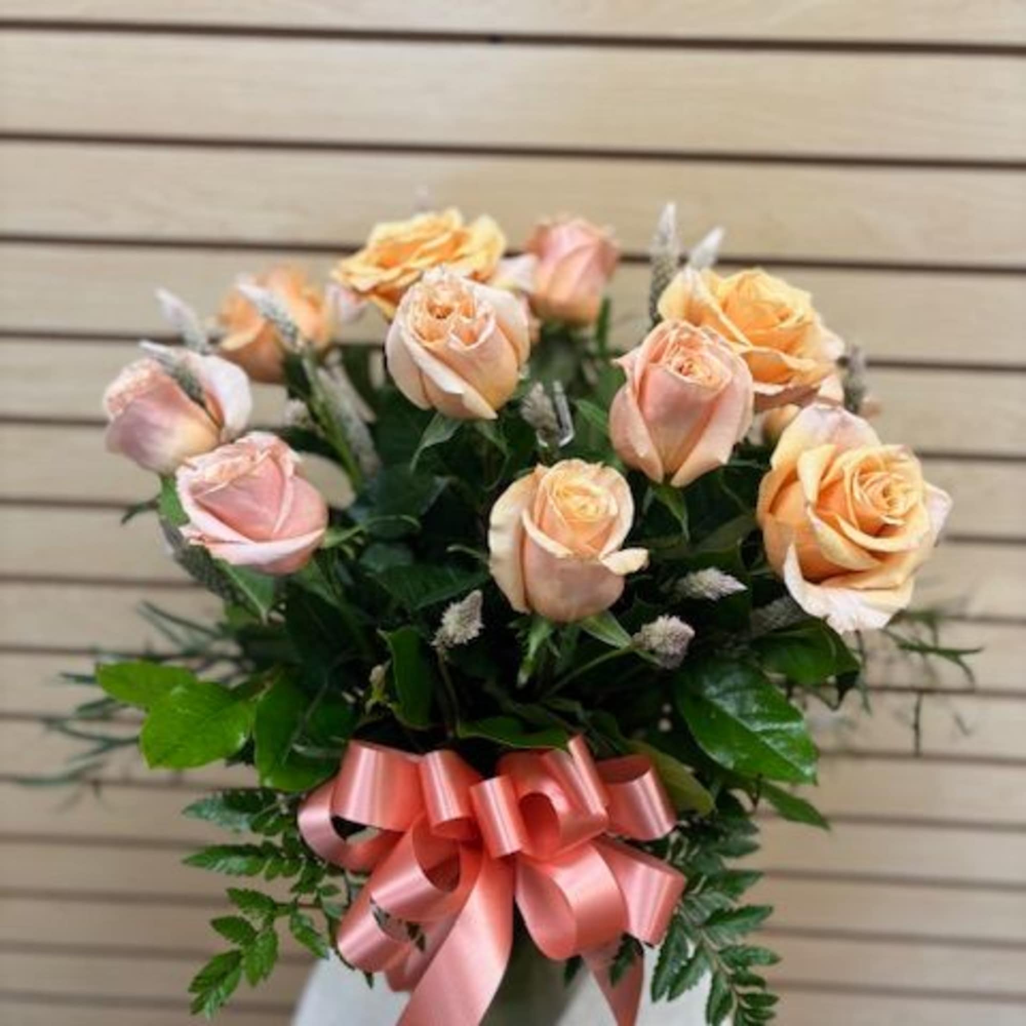 Peach and pink roses in a vase with a pink ribbon bow