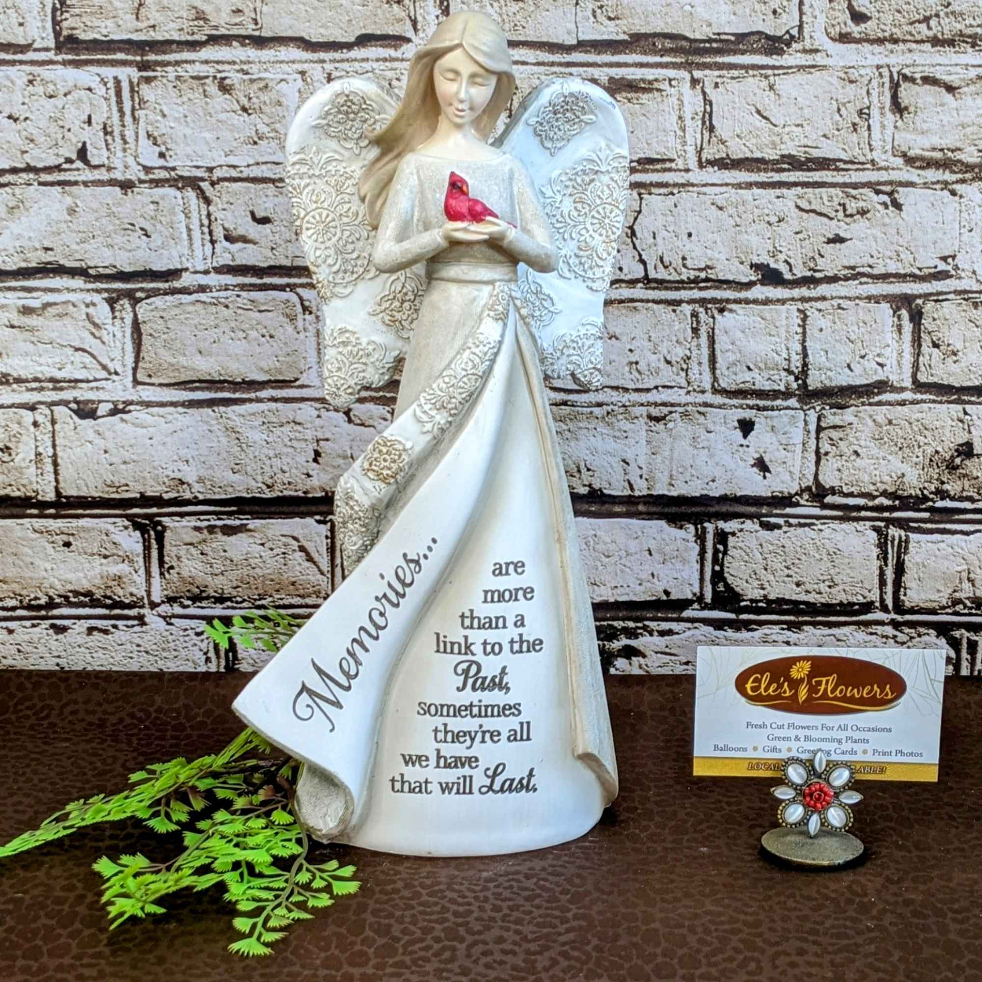 Angel figurine holding a red bird with a memorial message on the dress