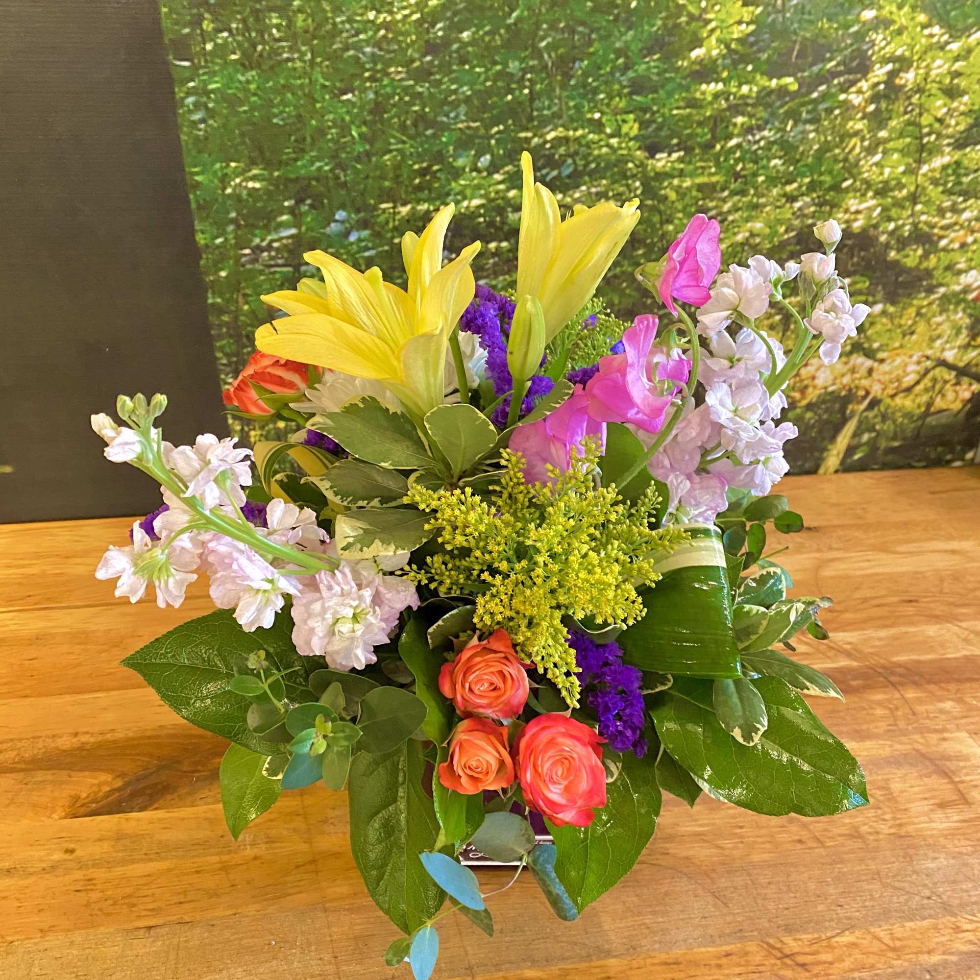Colorful bouquet with yellow lilies, pink roses, and pale lavender flowers
