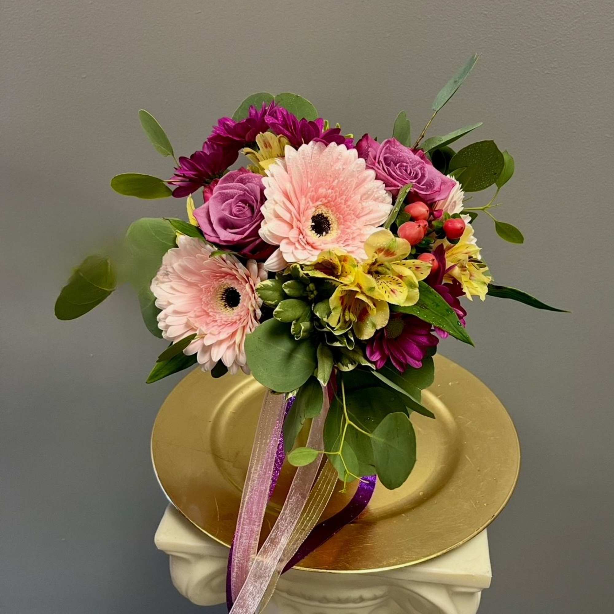 Bouquet of pink gerbera daisies, purple roses, and yellow alstroemeria