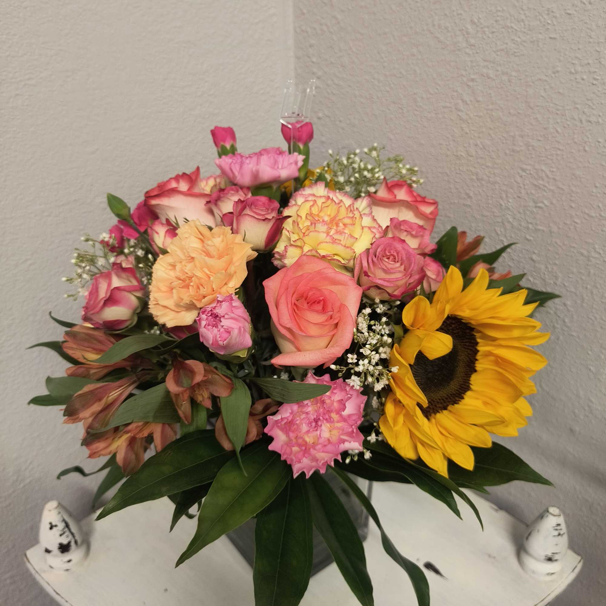 Mixed bouquet of roses, carnations, and a sunflower in a vase