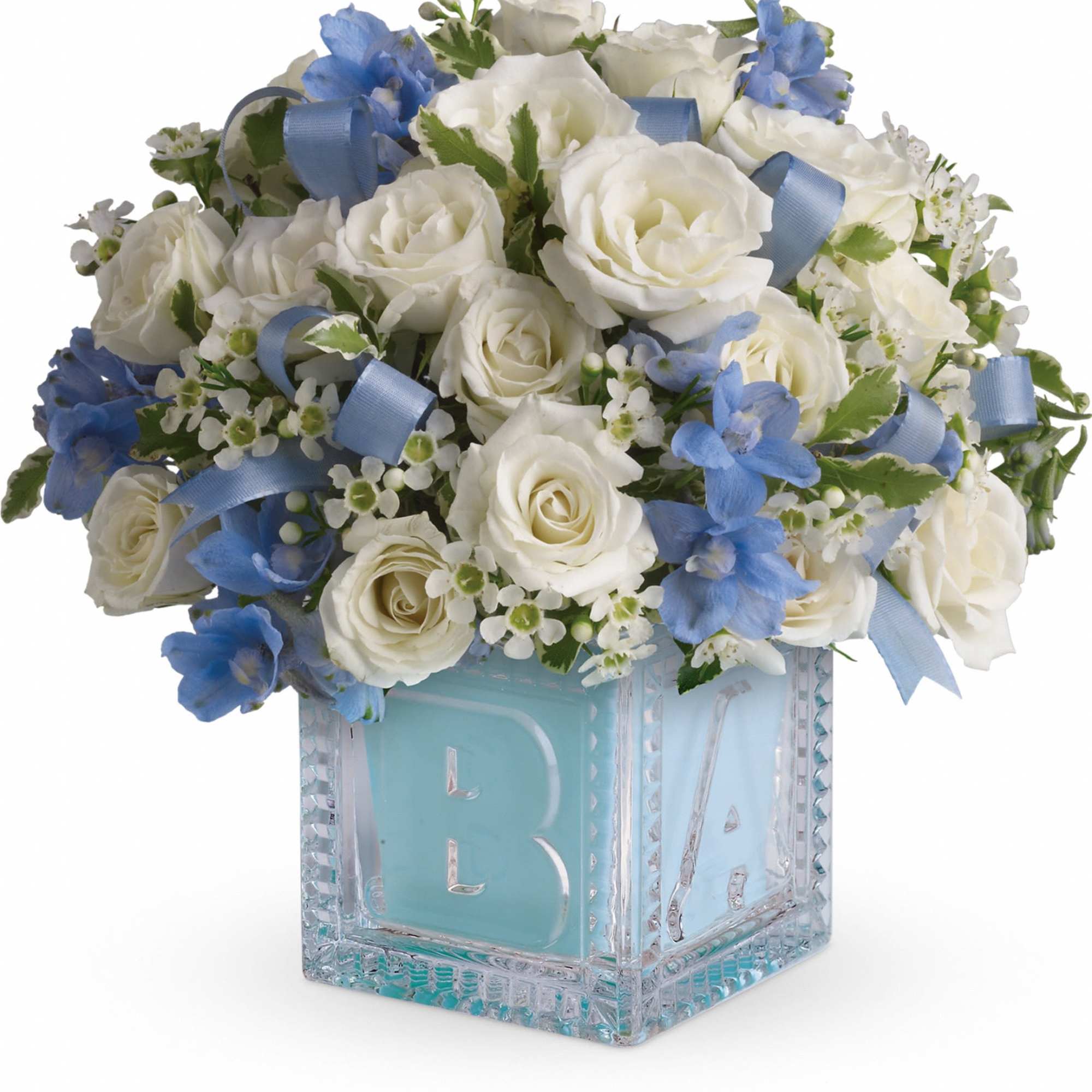 White roses and blue flowers in a glass block vase with a blue ribbon