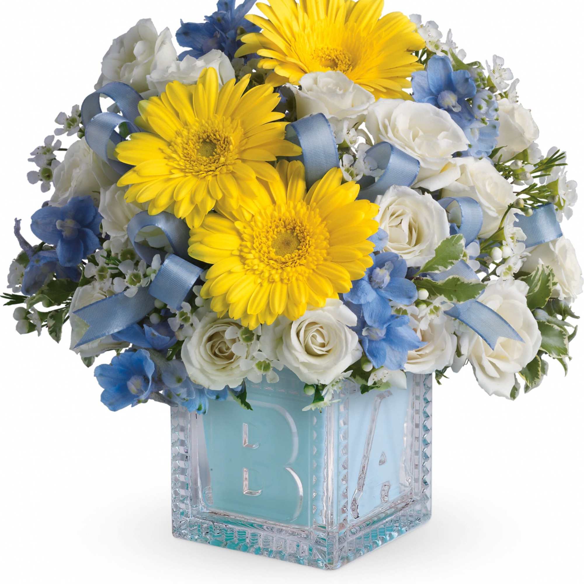 Yellow gerbera daisies and white roses in a glass cube vase with blue ribbon
