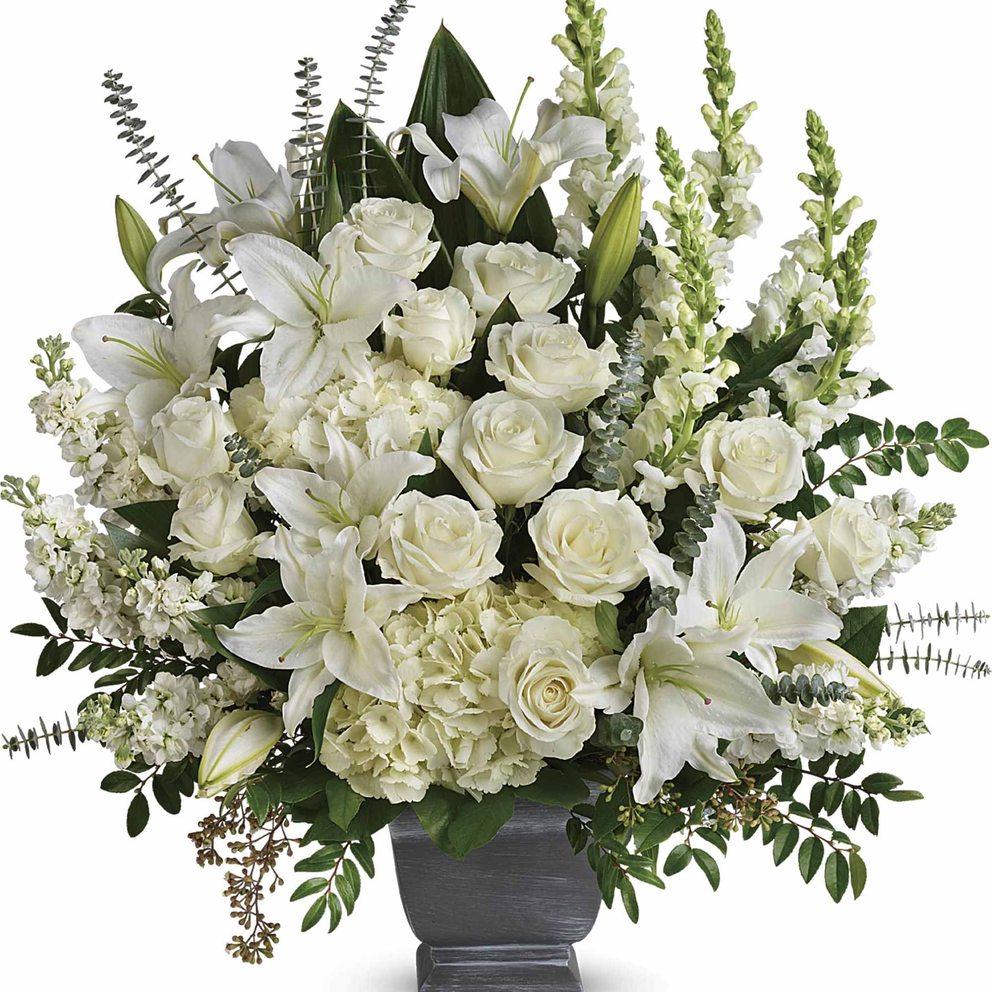 White roses and lilies arranged in a dark pedestal vase