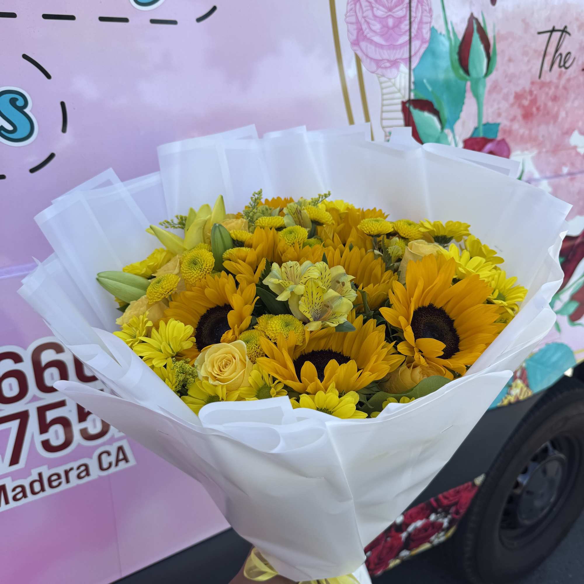 Bouquet of yellow sunflowers and roses wrapped in white paper