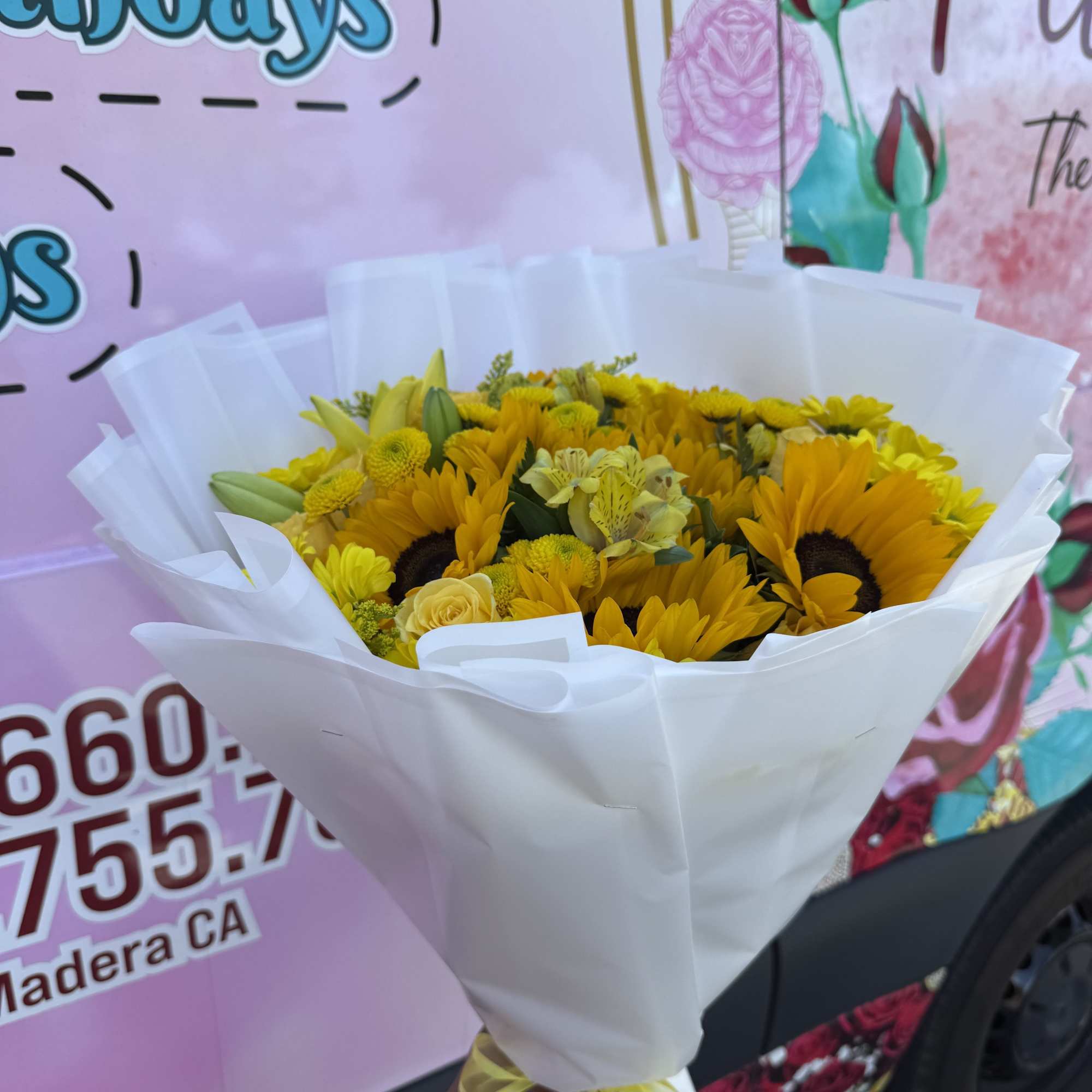 Bouquet of yellow sunflowers and mixed blooms wrapped in white paper