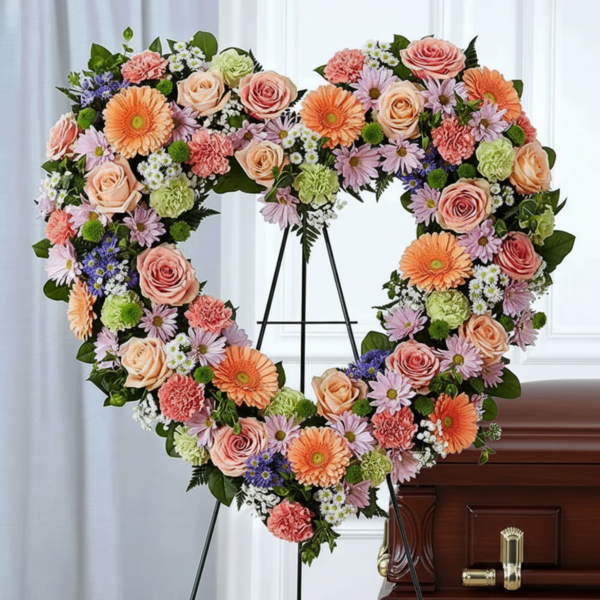 Heart-shaped floral spray on an easel beside a casket