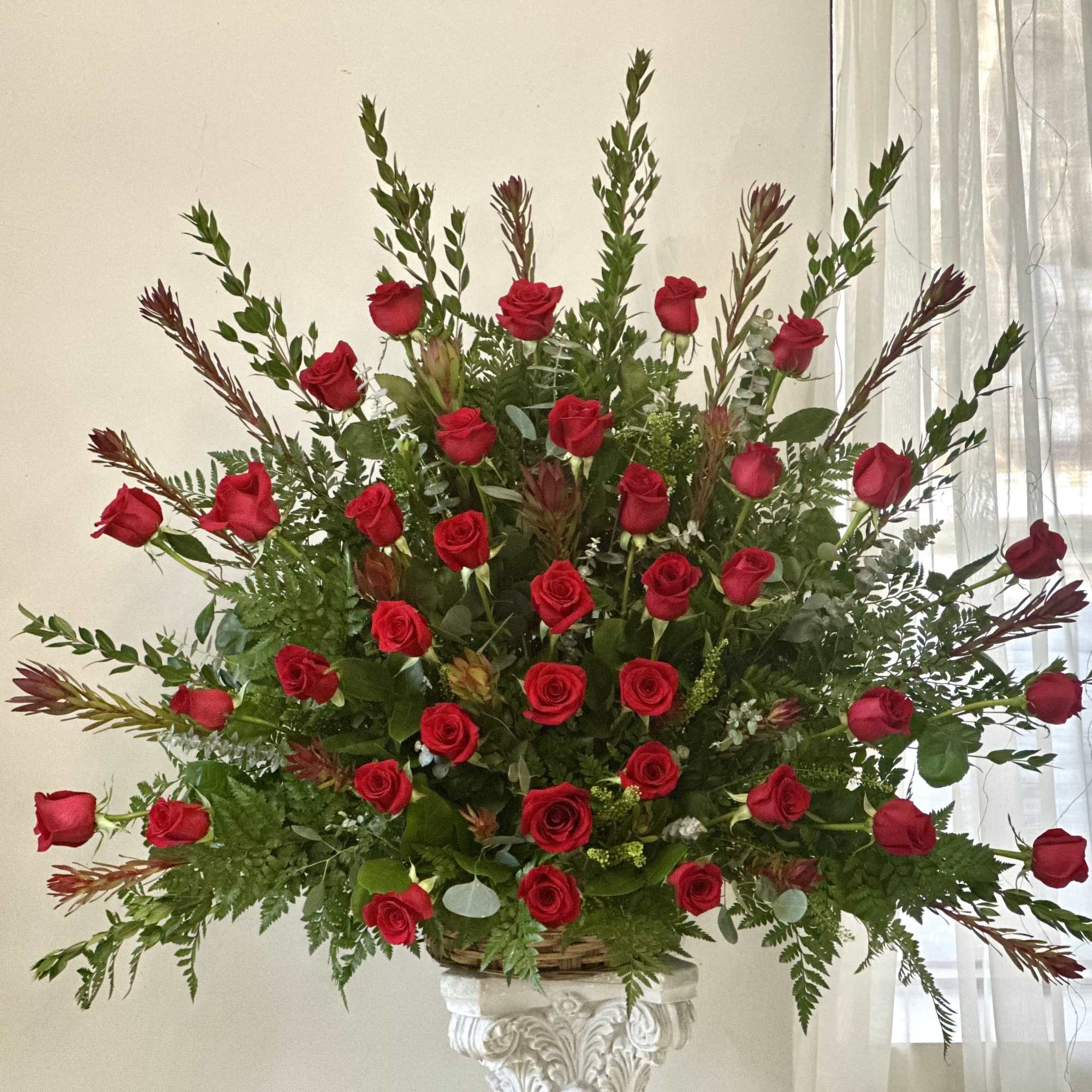 Large arrangement of red roses in a white pedestal vase