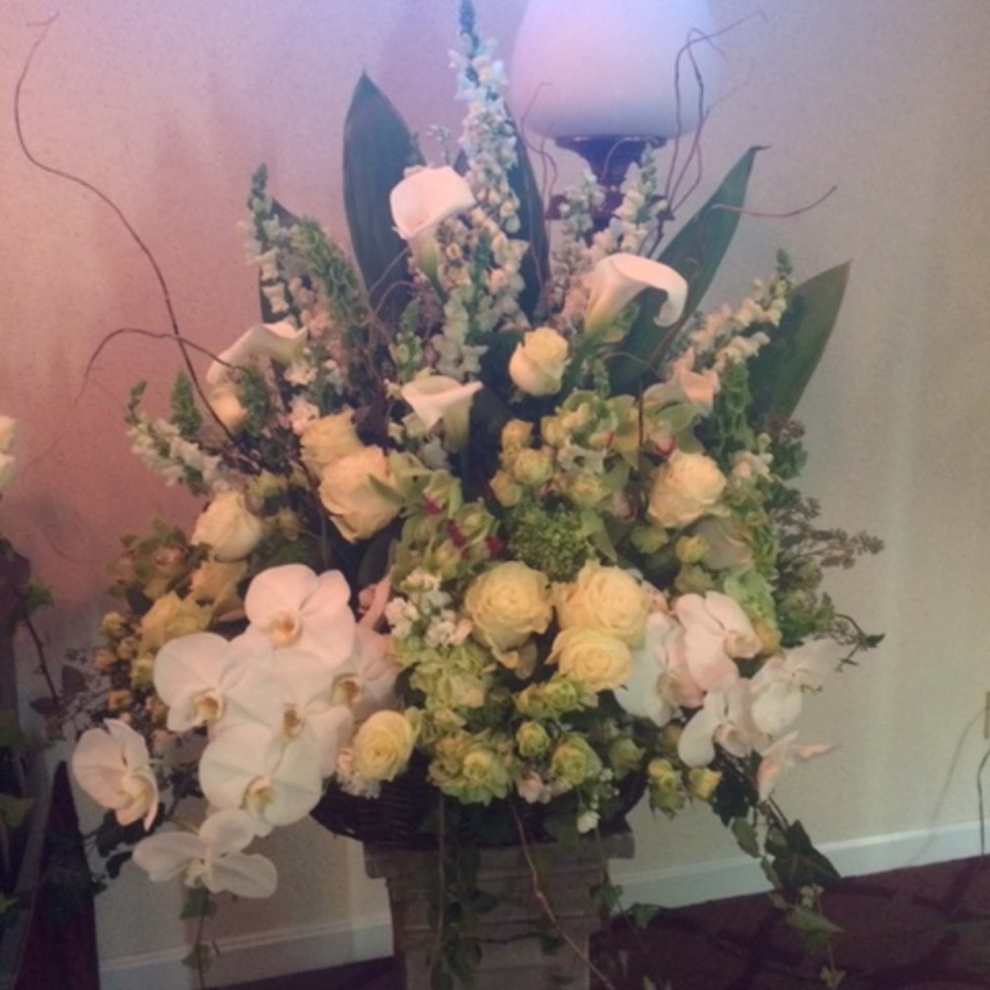 Large floral arrangement with white orchids and pale roses in a pedestal vase