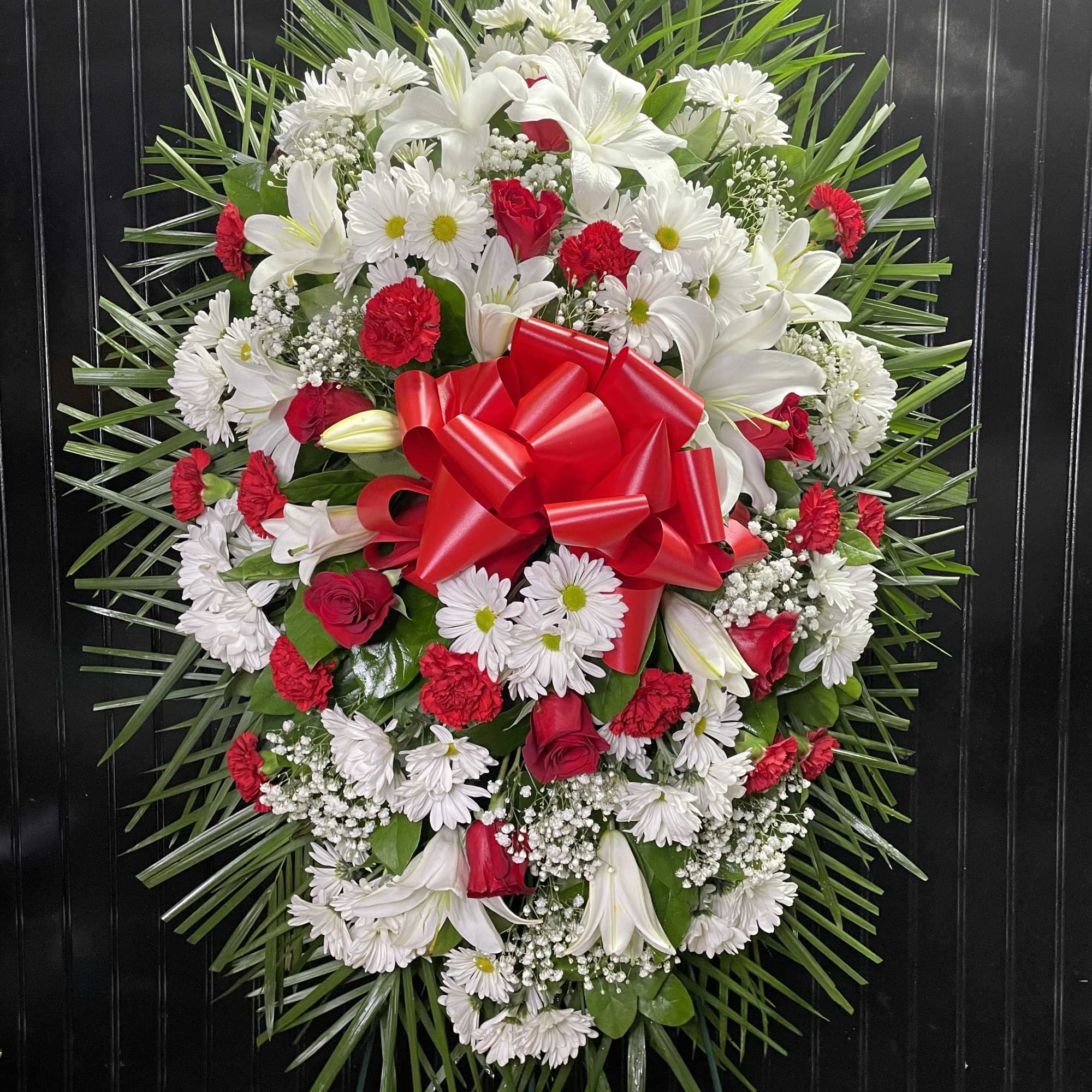 Heart-shaped wreath of white and red flowers with a large red bow
