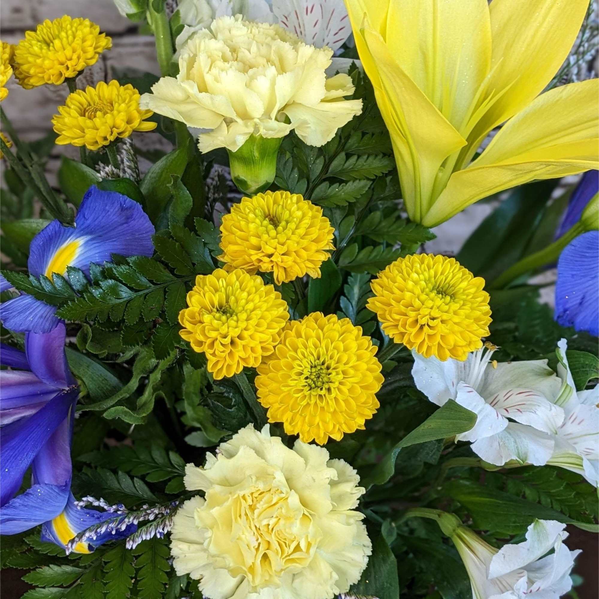 Mixed bouquet with yellow chrysanthemums, pale carnations, and blue iris