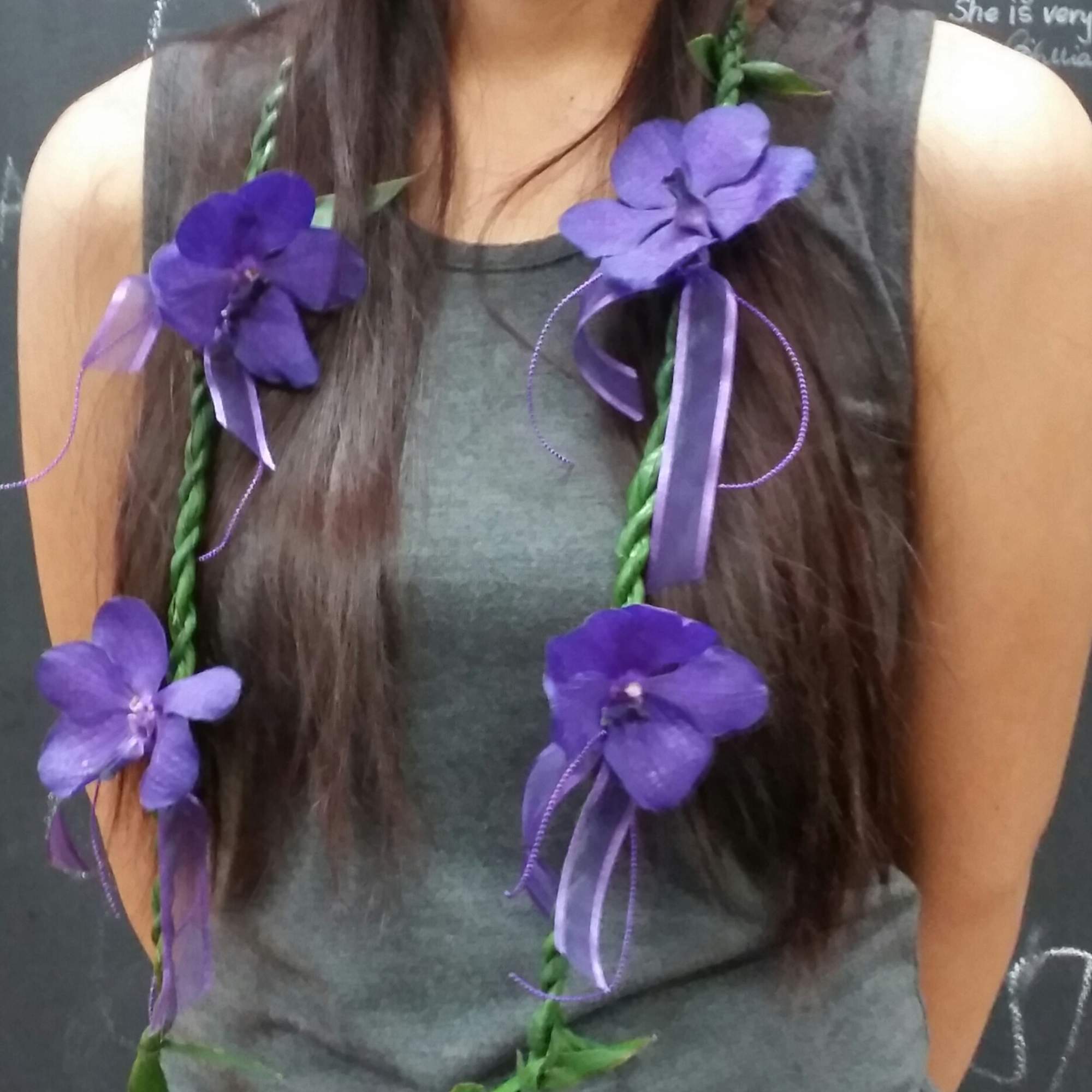 Woman wearing a purple flower lei with ribbon accents